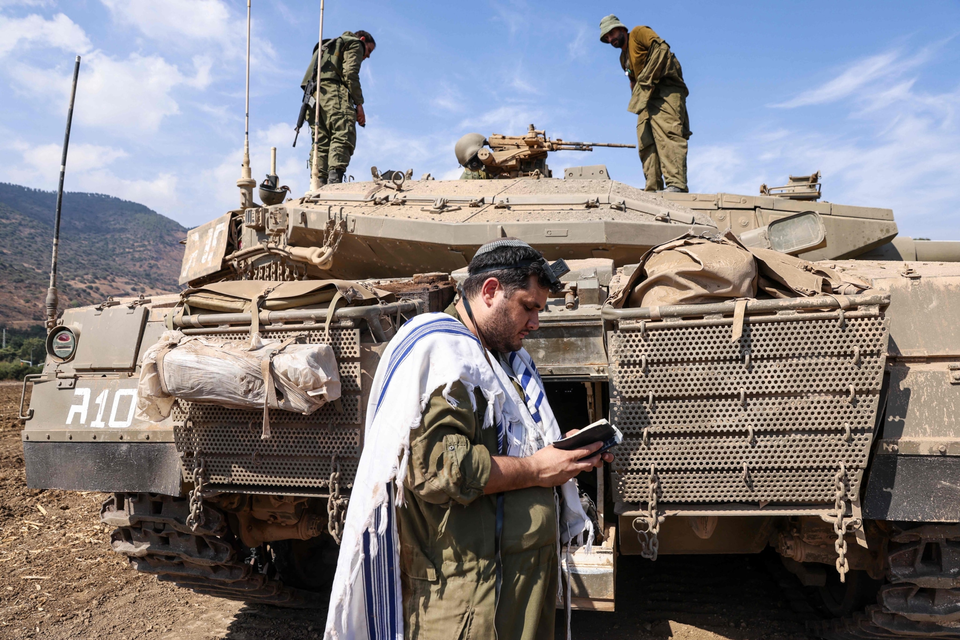 PHOTO: An Israeli sodleir prays standing in front of a Merkava tank on the outskirts of the northern town of Kiryat Shmona near the border with Lebanon on Oct. 8, 2023.