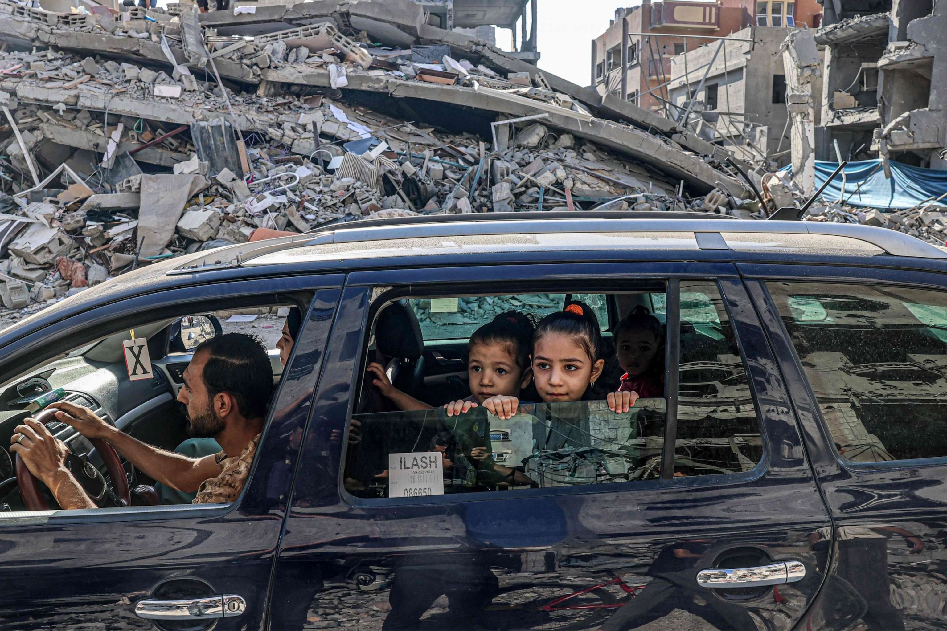 PHOTO: Palestinians drive amid the rubble of buildings destroyed in an Israeli air strike in Rafah, on the southern Gaza Strip on Oct. 12, 2023.