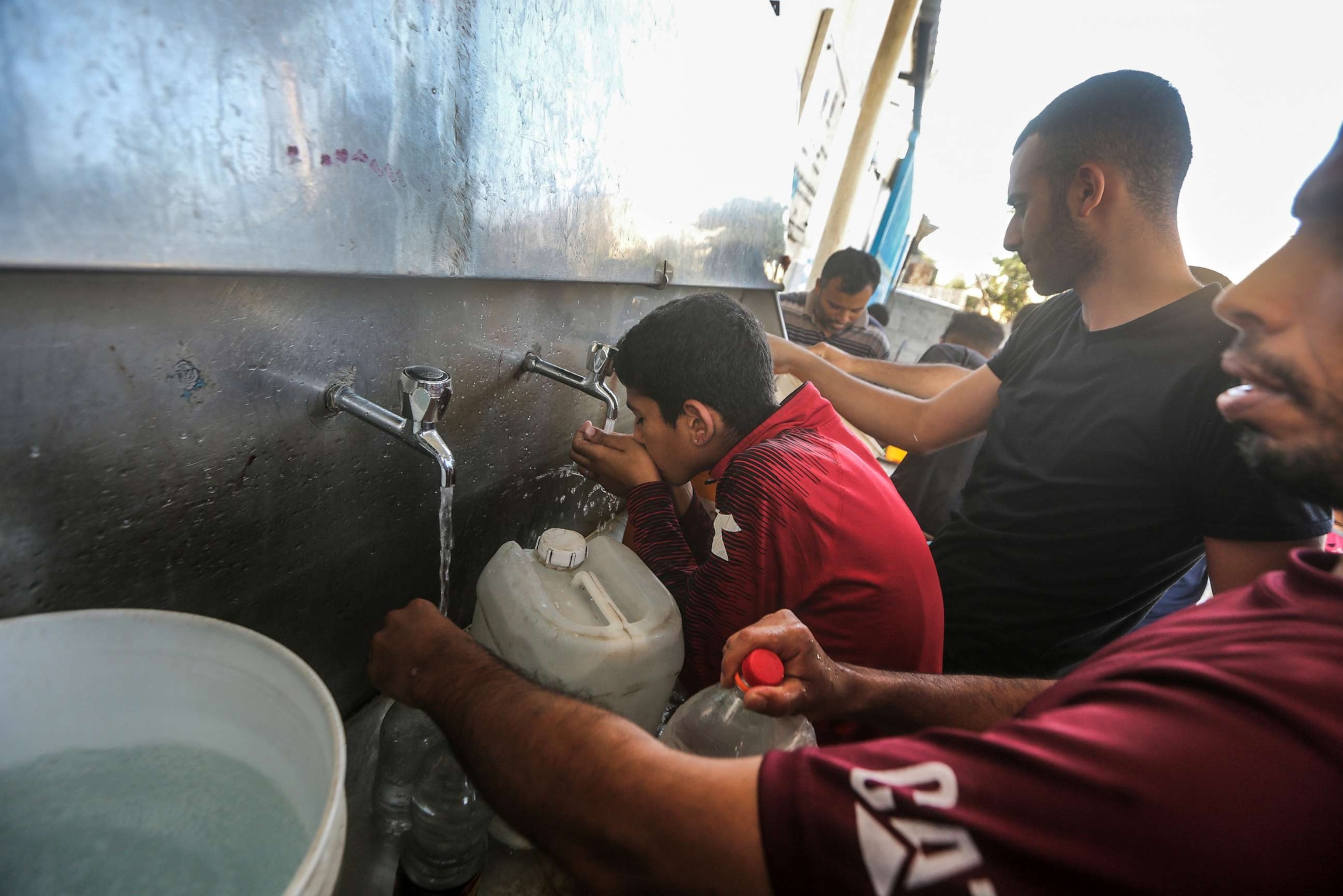 PHOTO: Palestinians fill containers with drinking water from a water distribution vehicle, amid the water crisis caused by the Israeli siege on the Gaza Strip.