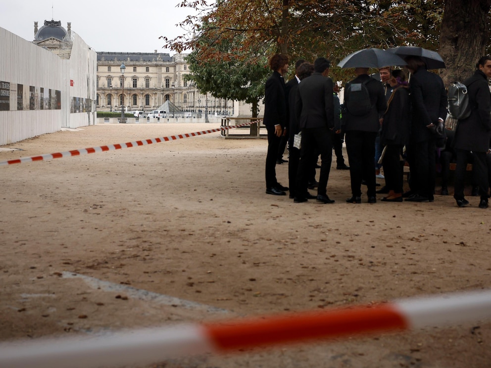 Staff wait after the evacuation of the Louvre museum, in Paris, Saturday Oct. 14, 2023. The Louvre Museum says it is closing for the day and evacuating all visitors and staff after a threat. (AP Photo/Thomas Padilla)