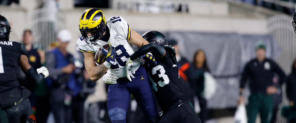 Michigan tight end Colston Loveland (18) is stopped by Michigan State defensive back Malik Spencer, right, during the first half of an NCAA college football game, Saturday, Oct. 21, 2023, in East Lansing, Mich. (AP Photo/Al Goldis)