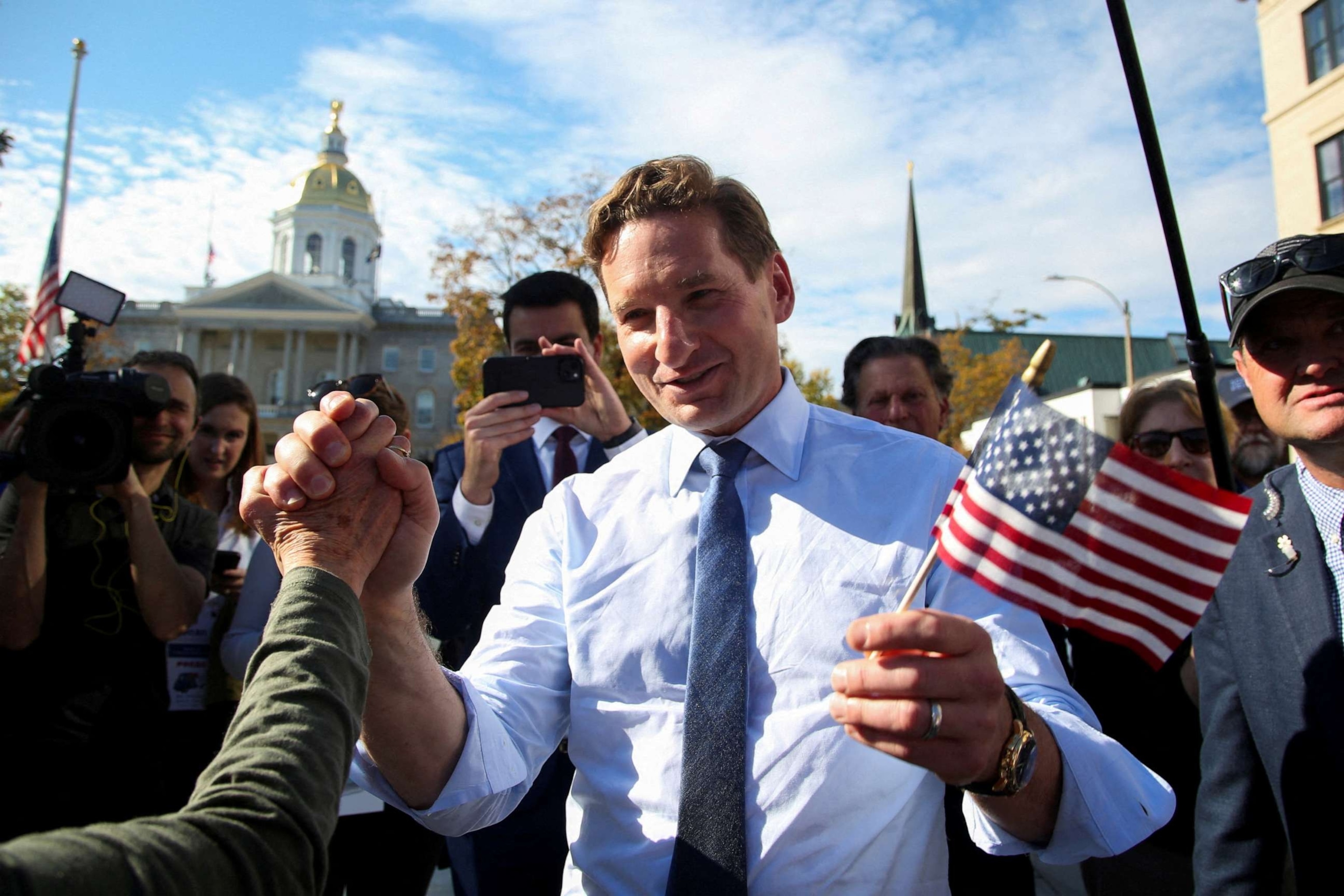 PHOTO: Democratic presidential candidate Representative Dean Phillips holds hands with a supporter after filing the paperwork to put his name on the ballot for the state's primary election outside the statehouse in Concord, N. H., on Oct. 27, 2023.