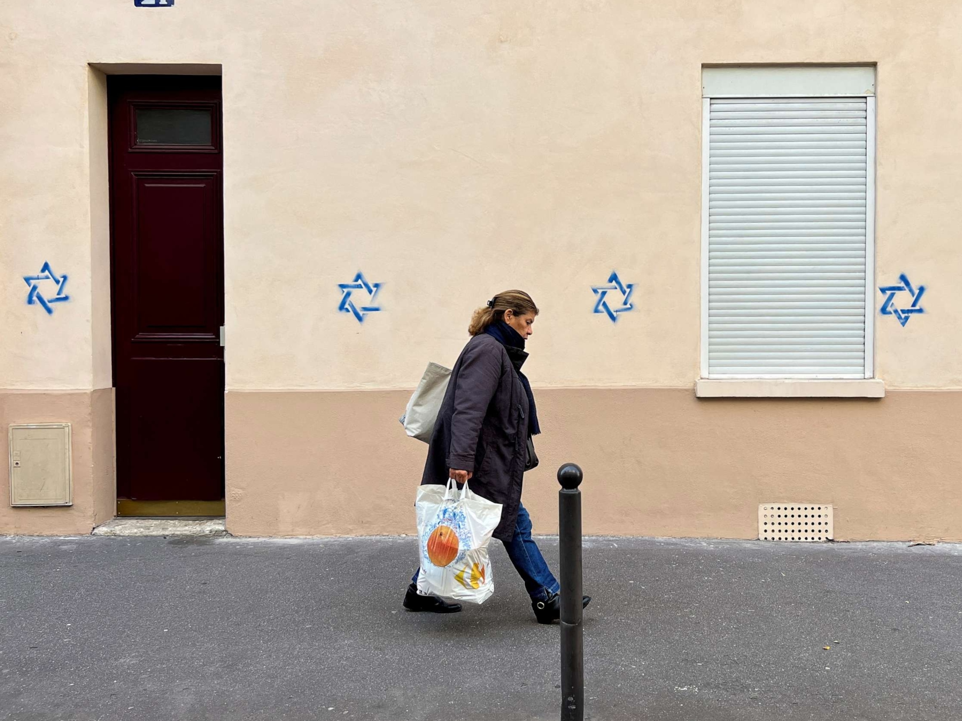 PHOTO: A woman walks past a building tagged with Star of David symbols in Paris, France, October 31, 2023