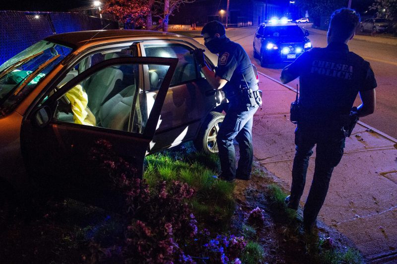 Officer Daniel Arteaga and other officers inspect the car that they were chasing, now crashed into a fence after hitting a fire hydrant in Chelsea, Massachusetts on May 1, 2021. - Chelsea, a 2.2 square-mile (5.7 square km) city, has a population of close to 40,000 people made up of mostly people of Latino or Hispanic origin, 67% according to the US Census Bureau. The Bureau also reports that 18% of the population lives at the poverty line. The Chelsea Police Department considers itself ahead of many parts of theUS when it comes to community policing and the way it deals with de-escalating domestic and criminal situations. (Photo by Joseph Prezioso / AFP) (Photo by JOSEPH PREZIOSO/AFP via Getty Images)