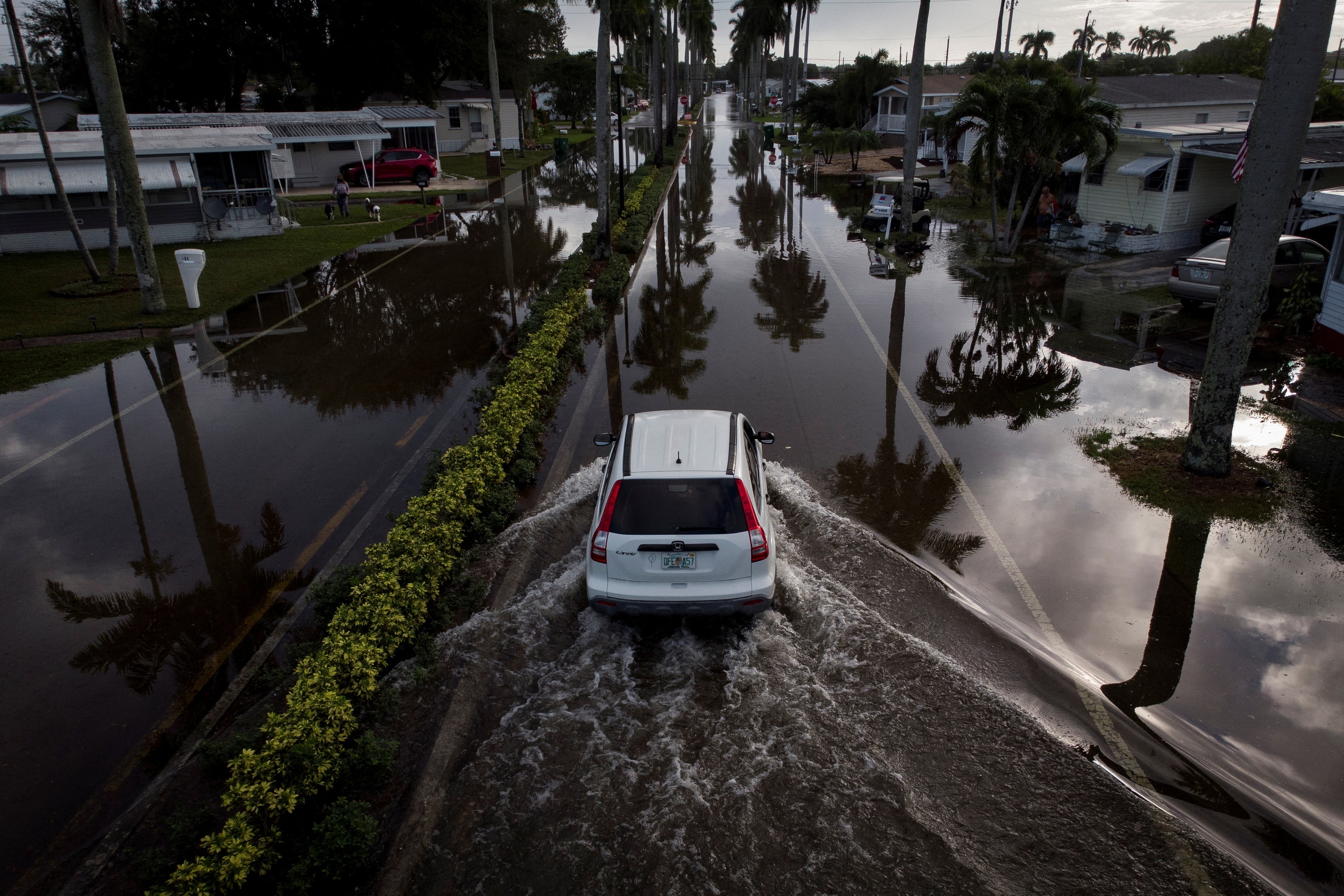 PHOTO: A car drives through flood water, in a trailer park community in Davie, Florida, November 16, 2023.