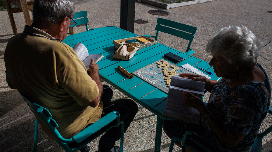 Two elderly individuals playing Scrabble