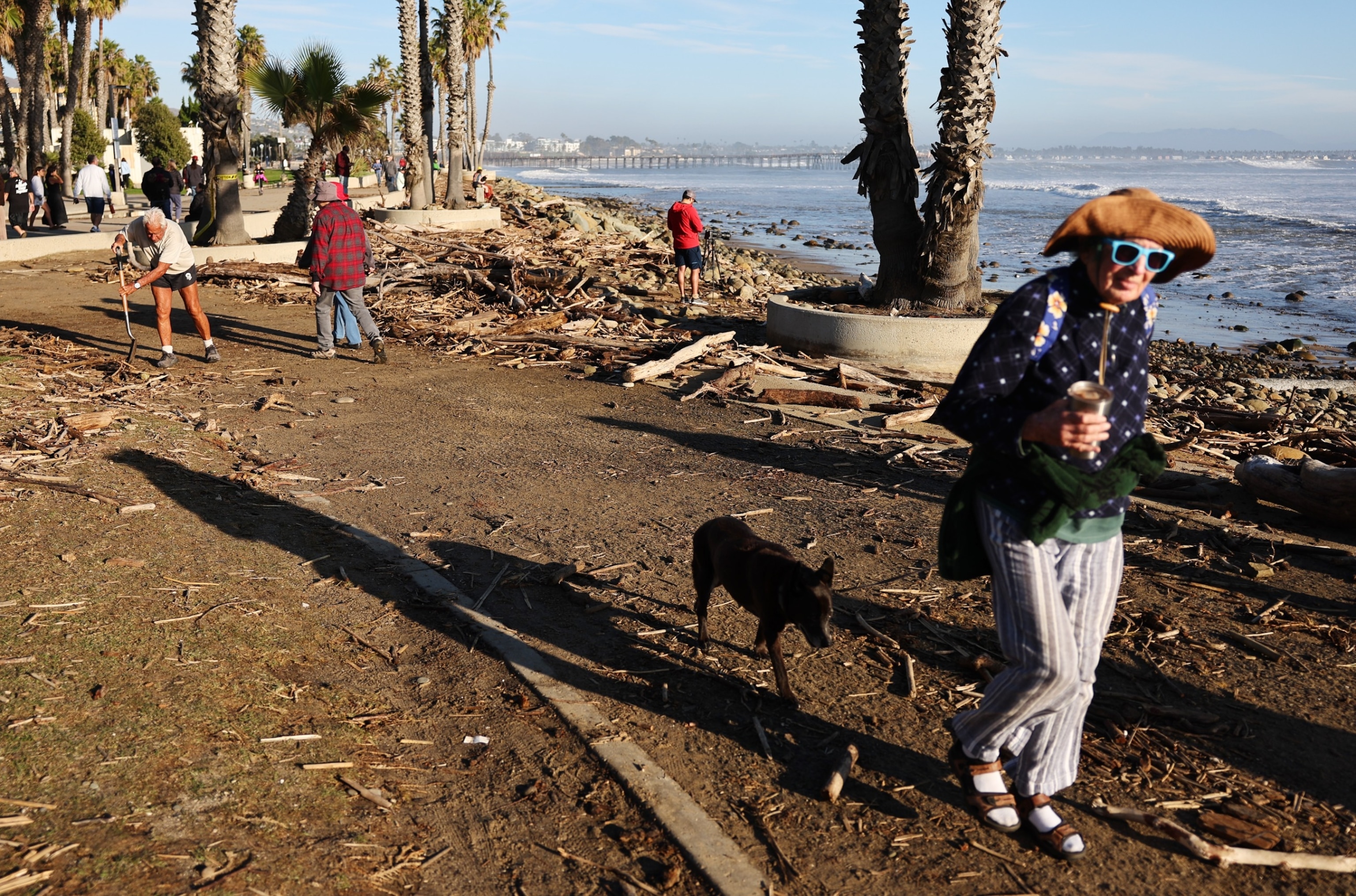 PHOTO: A person attempts to clean up debris washed up by large waves which impacted the beach on Dec. 28, 2023, in Ventura, California