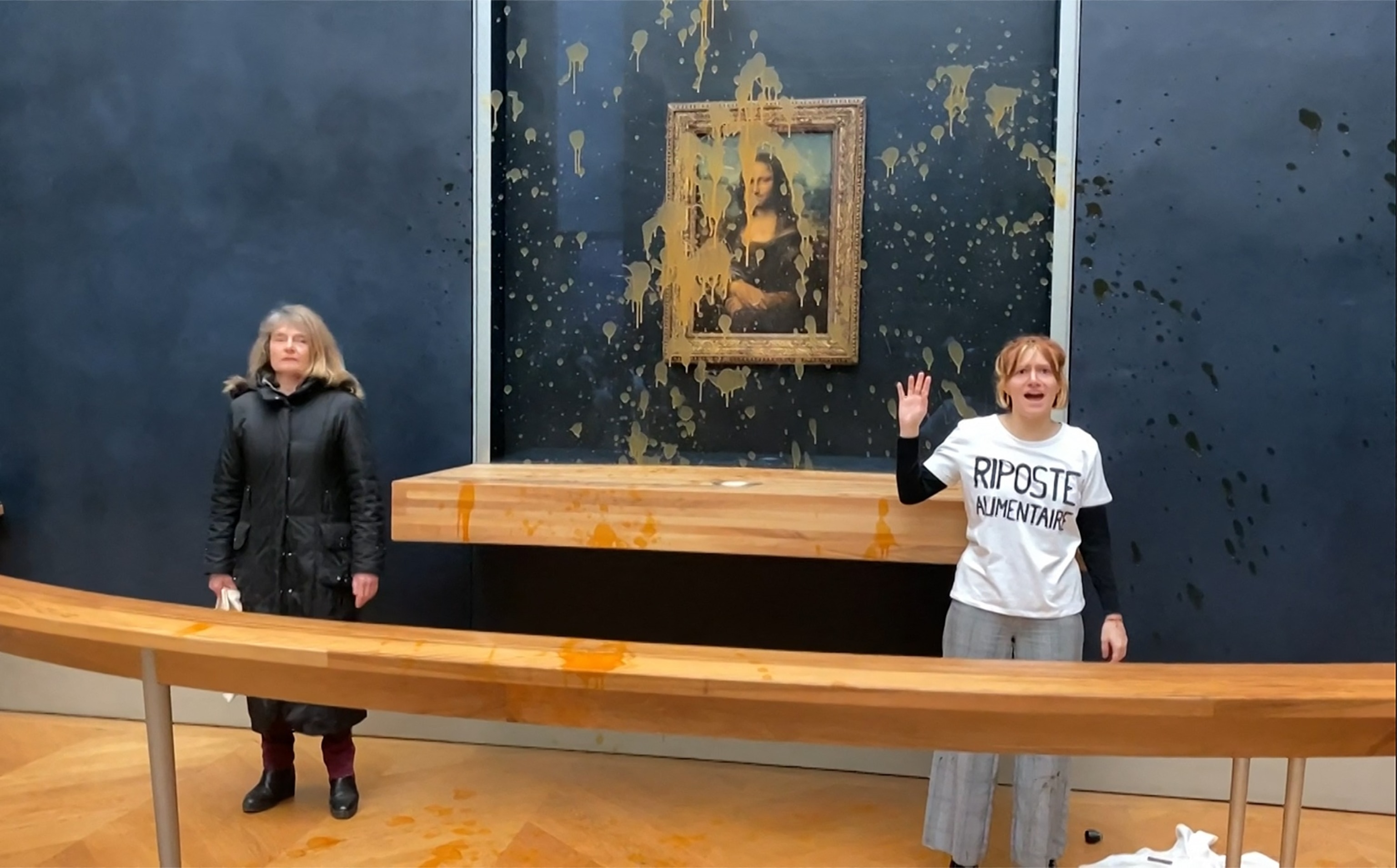 PHOTO: This image grab taken from AFPTV footage shows two environmental activists from the collective dubbed "Riposte Alimentaire" gesturing as they stand in front of the "Mona Lisa" painting at the Louvre museum in Paris, on Jan. 28, 2024. 