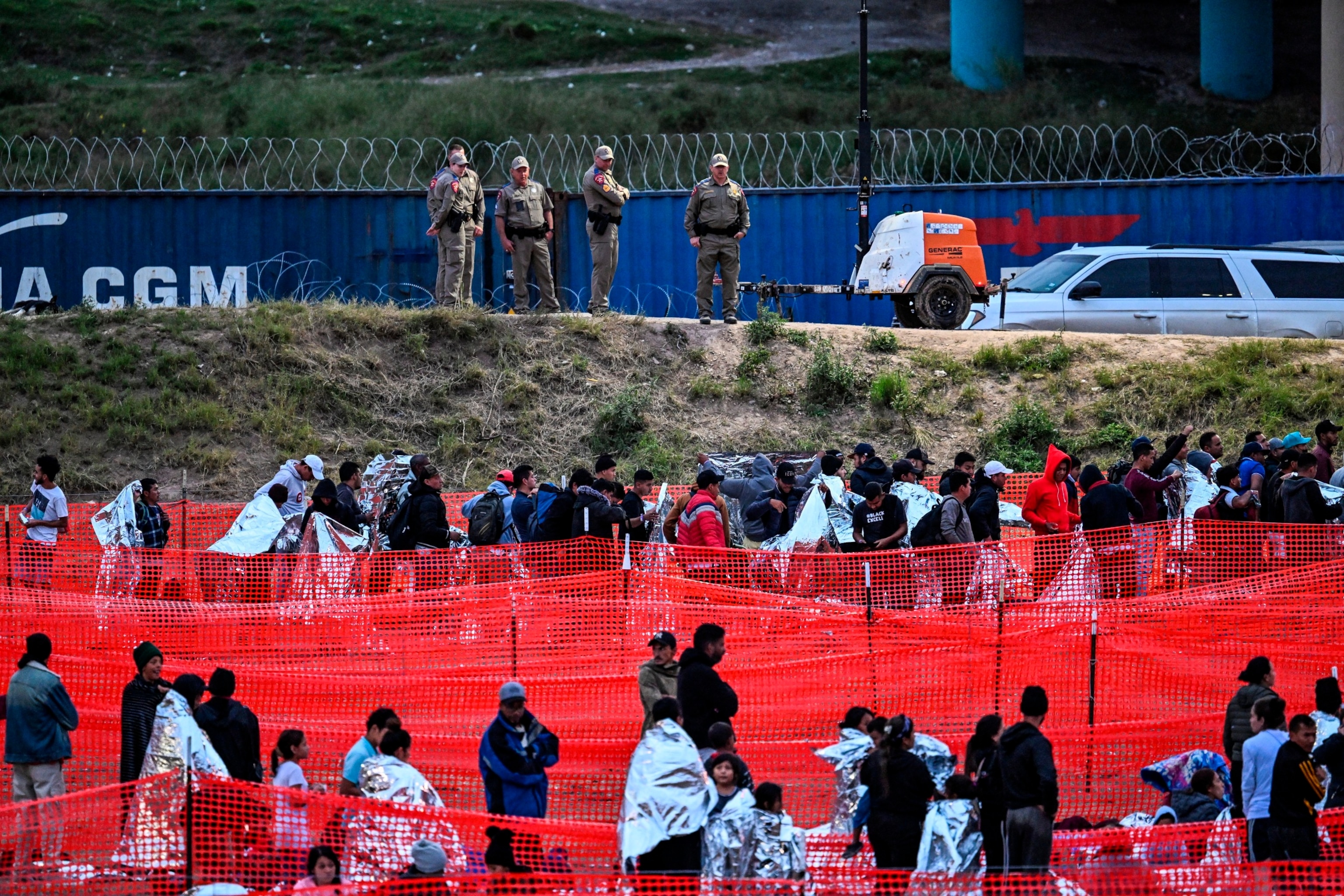 PHOTO: Customs and Border Protection agents stand guard as immigrants wait to be processed at a US Border Patrol transit center after crossing the border from Mexico at Eagle Pass, Texas, on Dec. 22, 2023. 