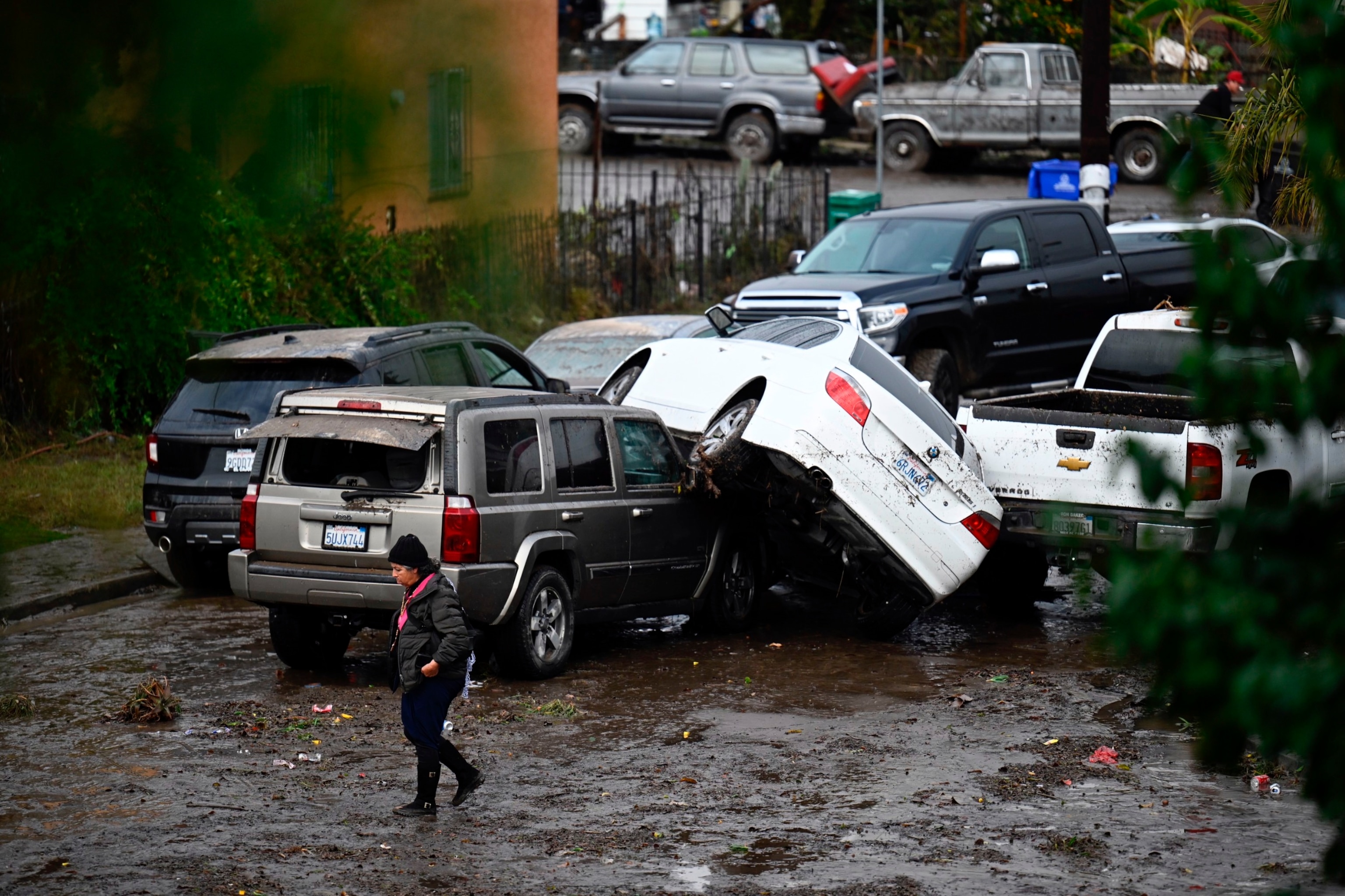 PHOTO: A woman walks by cars damaged from floods during a rain storm, Jan. 22, 2024, in San Diego. 