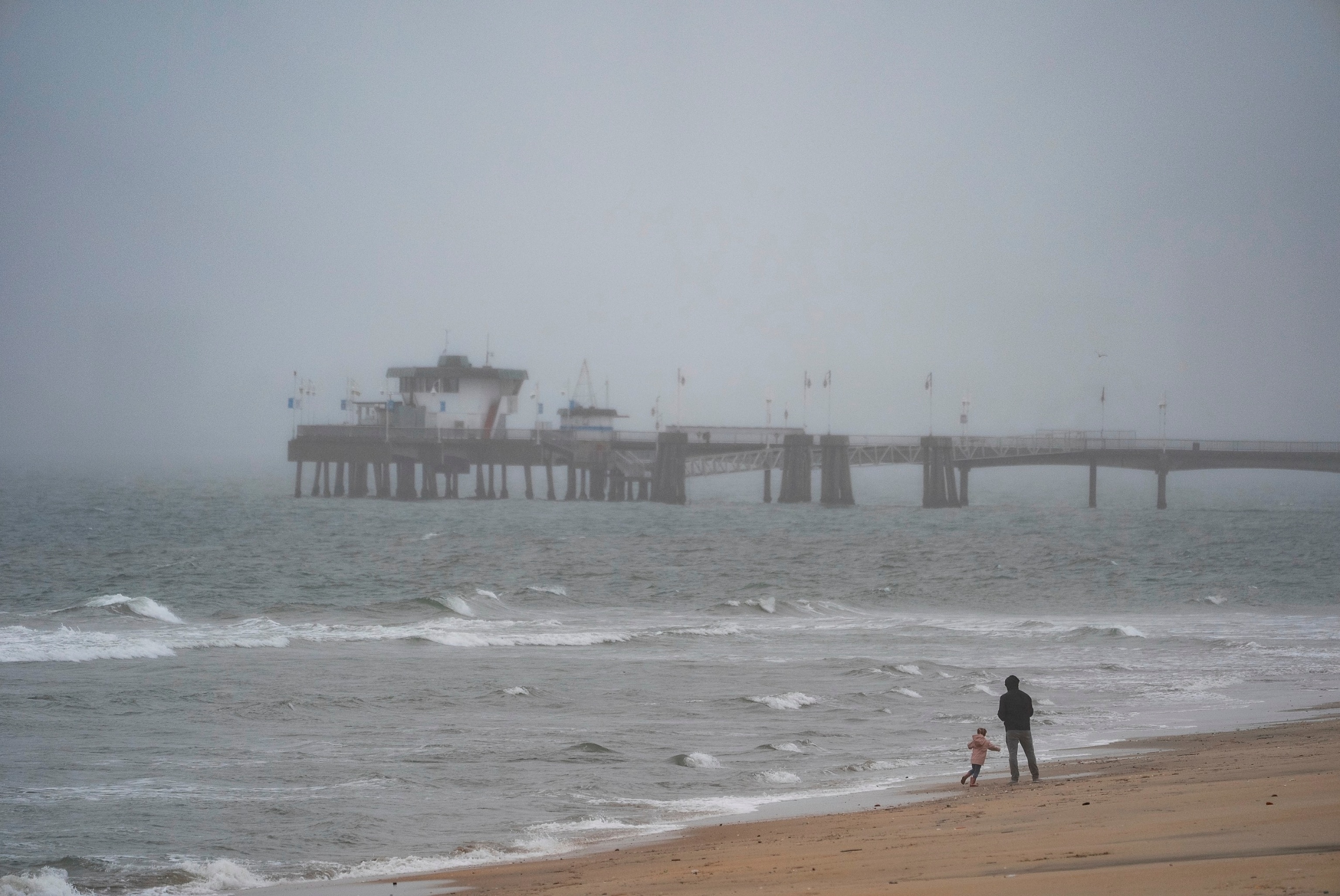 PHOTO: People walk on a beach in the rain in Long Beach, CA, Feb. 19, 2024. 