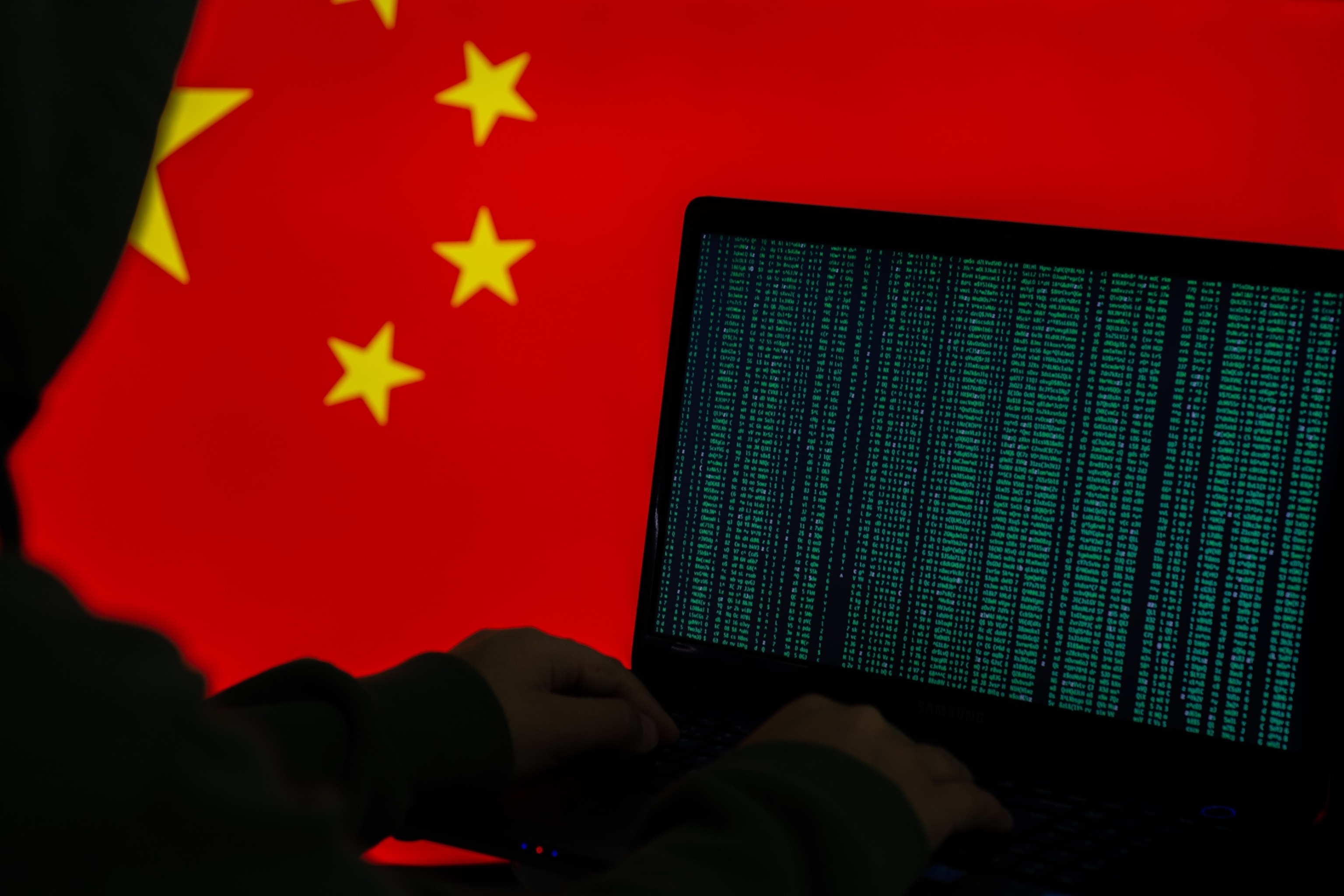 PHOTO: Hacker using a computer with a Chinese flag in the background.