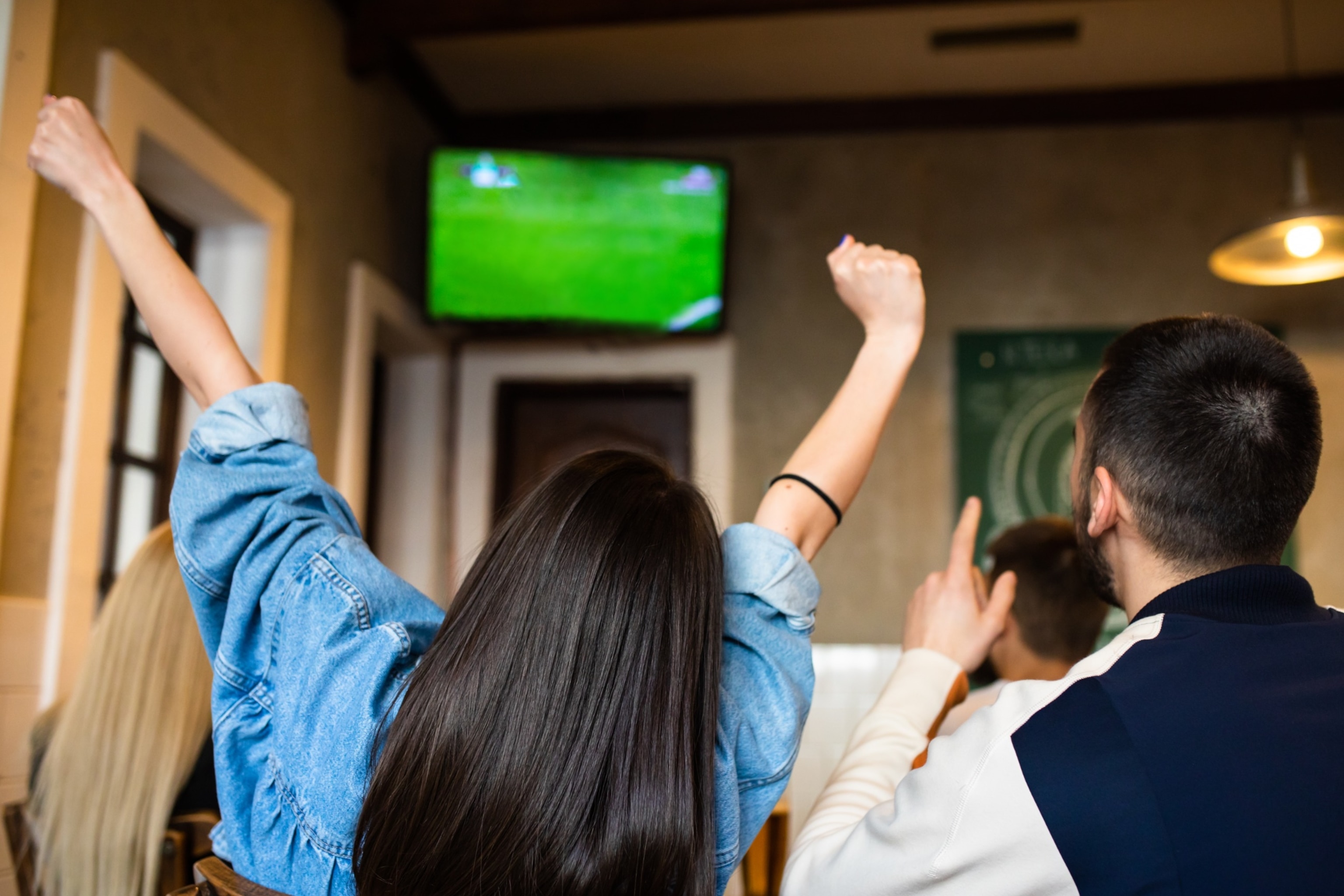 PHOTO: A group of friends watching a football game on TV at a bar.