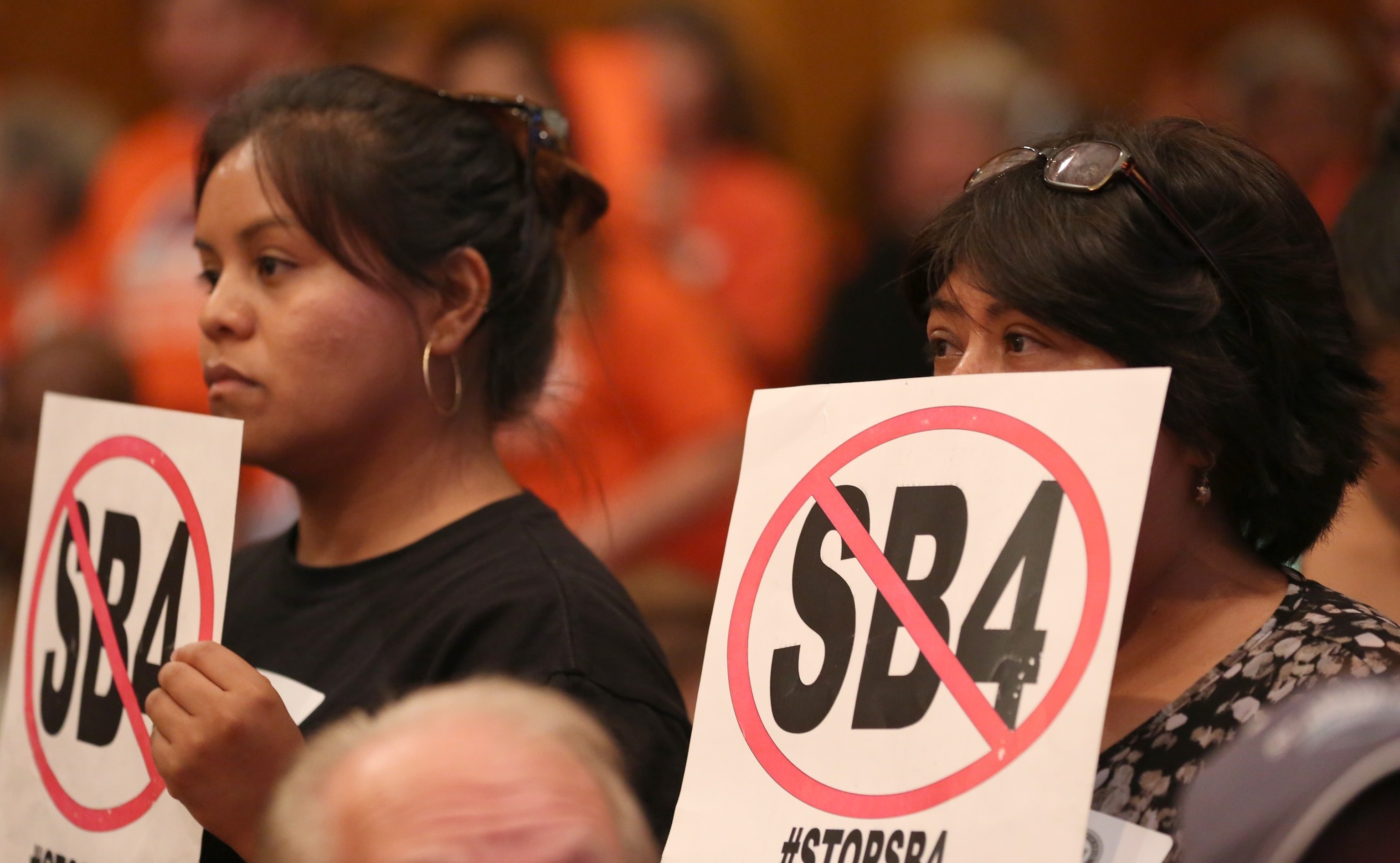 PHOTO: Two women hold up signs in opposition of Senate Bill 4 during a council meeting at City Hall, June 20, 2017, in Houston.