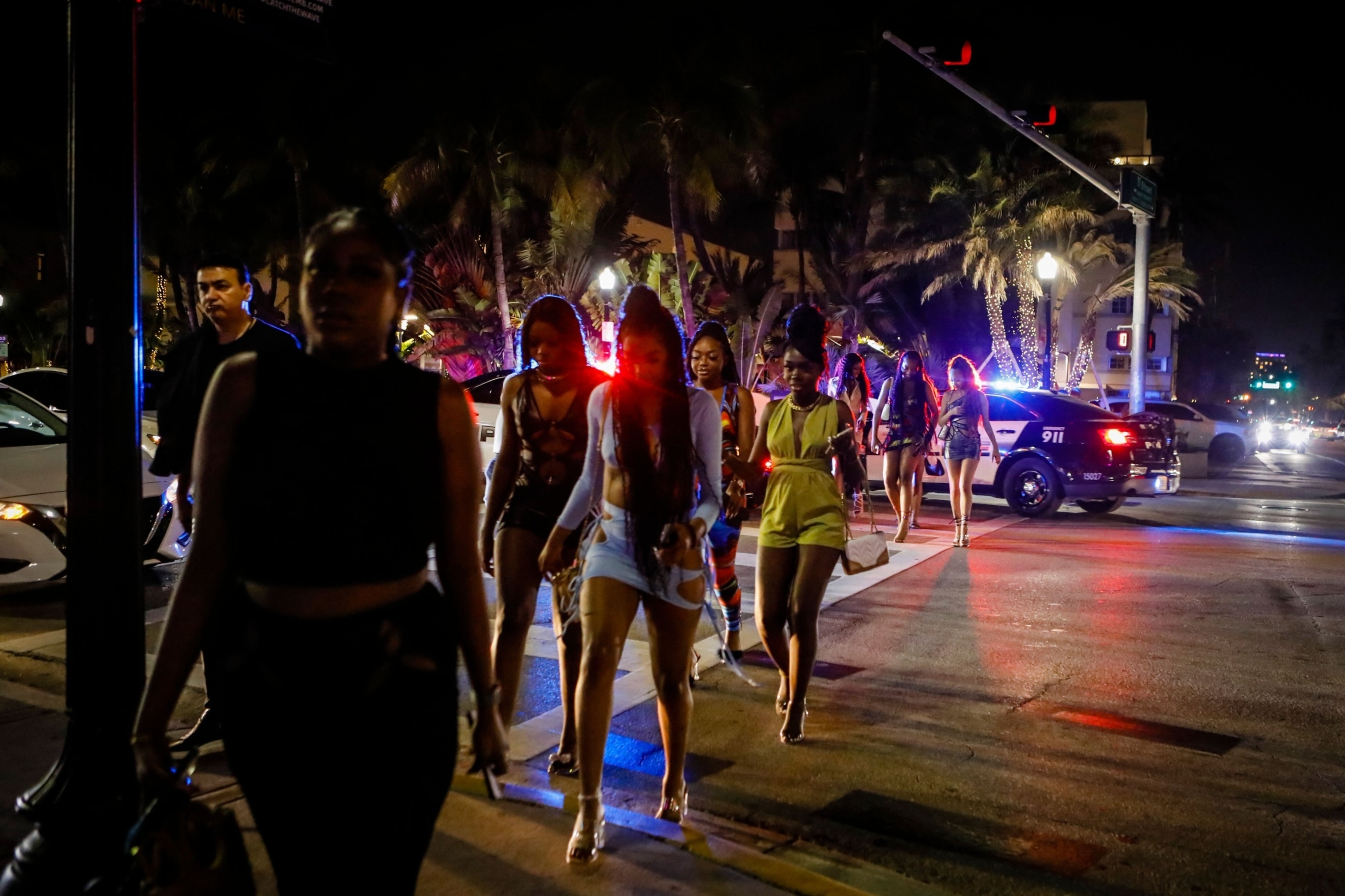 PHOTO: People walk on Ocean Drive with Police in the back during Spring Break in Miami Beach, Florida, on March 24, 2022.