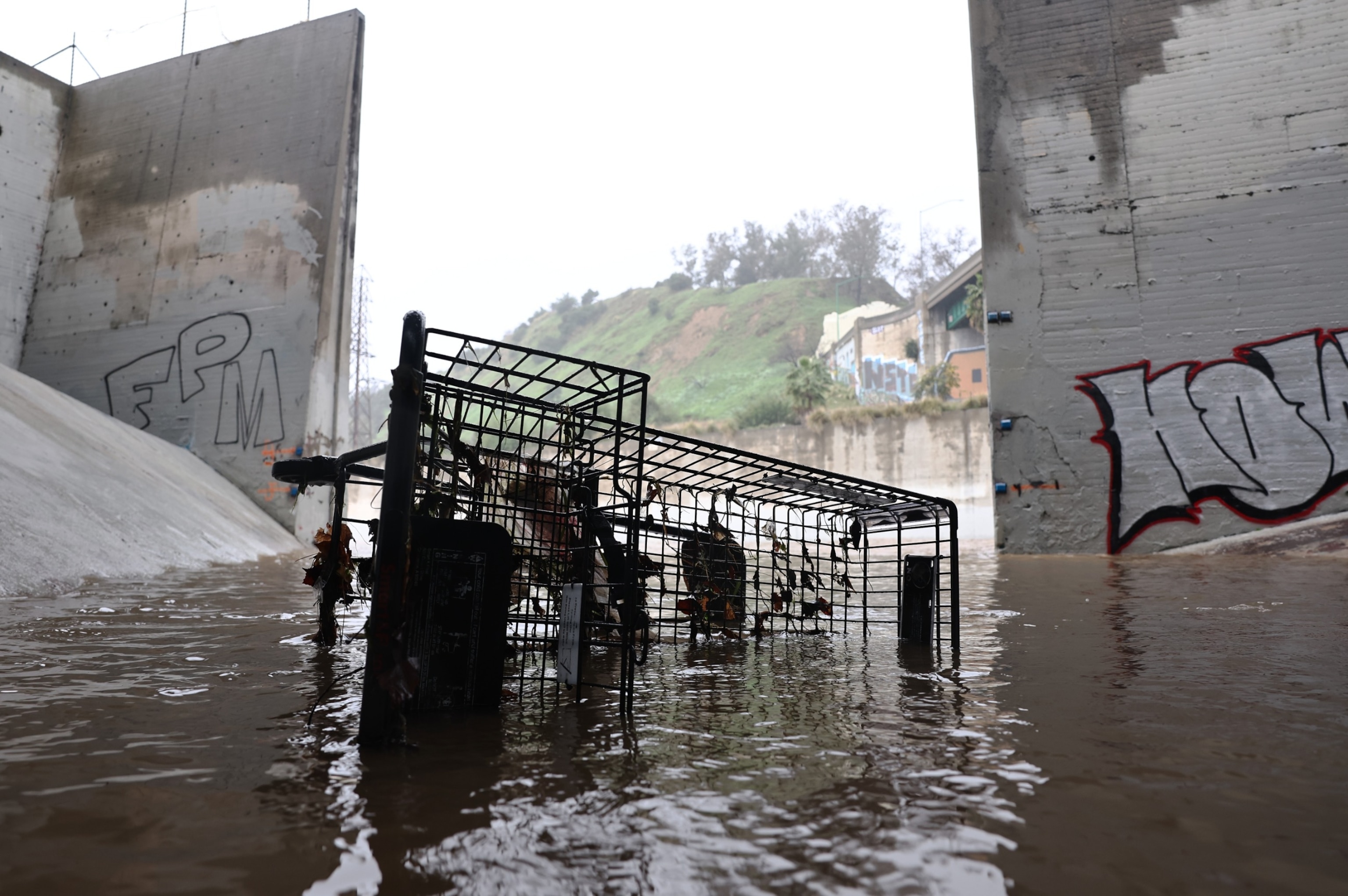 PHOTO: A shopping cart sits in an overflow area of the Los Angeles River, swollen by storm runoff, Feb. 19, 2024, in Los Angeles.