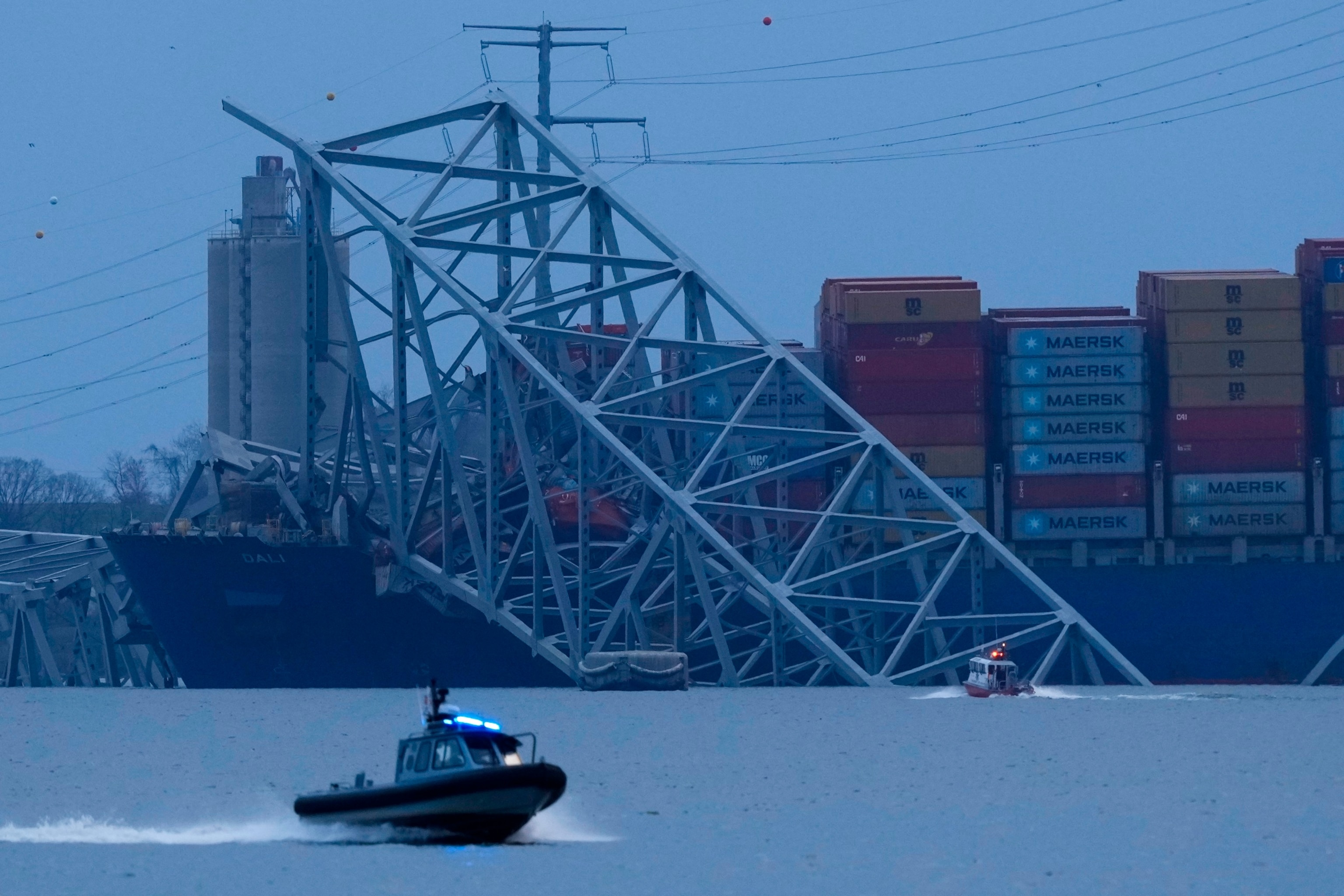 PHOTO: A container ship rests against wreckage of the Francis Scott Key Bridge as night falls on March 26, 2024, as seen from Sparrows Point, Md.