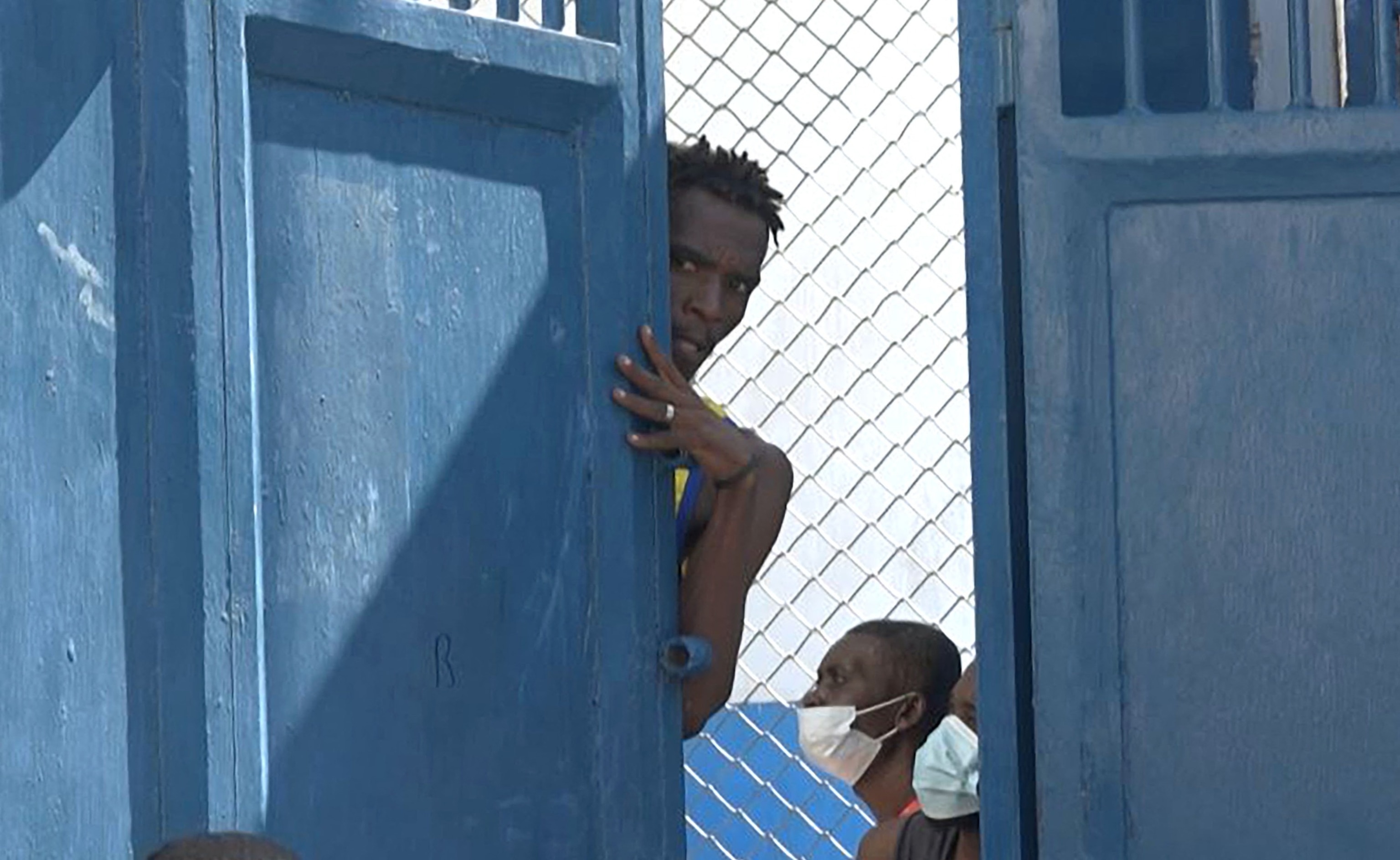 PHOTO: This screen grab taken from AFPTV shows a person looking out from behind a door near the National Penitentiary in Port-au-Prince, Haiti, on March 3, 2024, after armed gangs attacked the country's largest prison and freed scores of inmates.