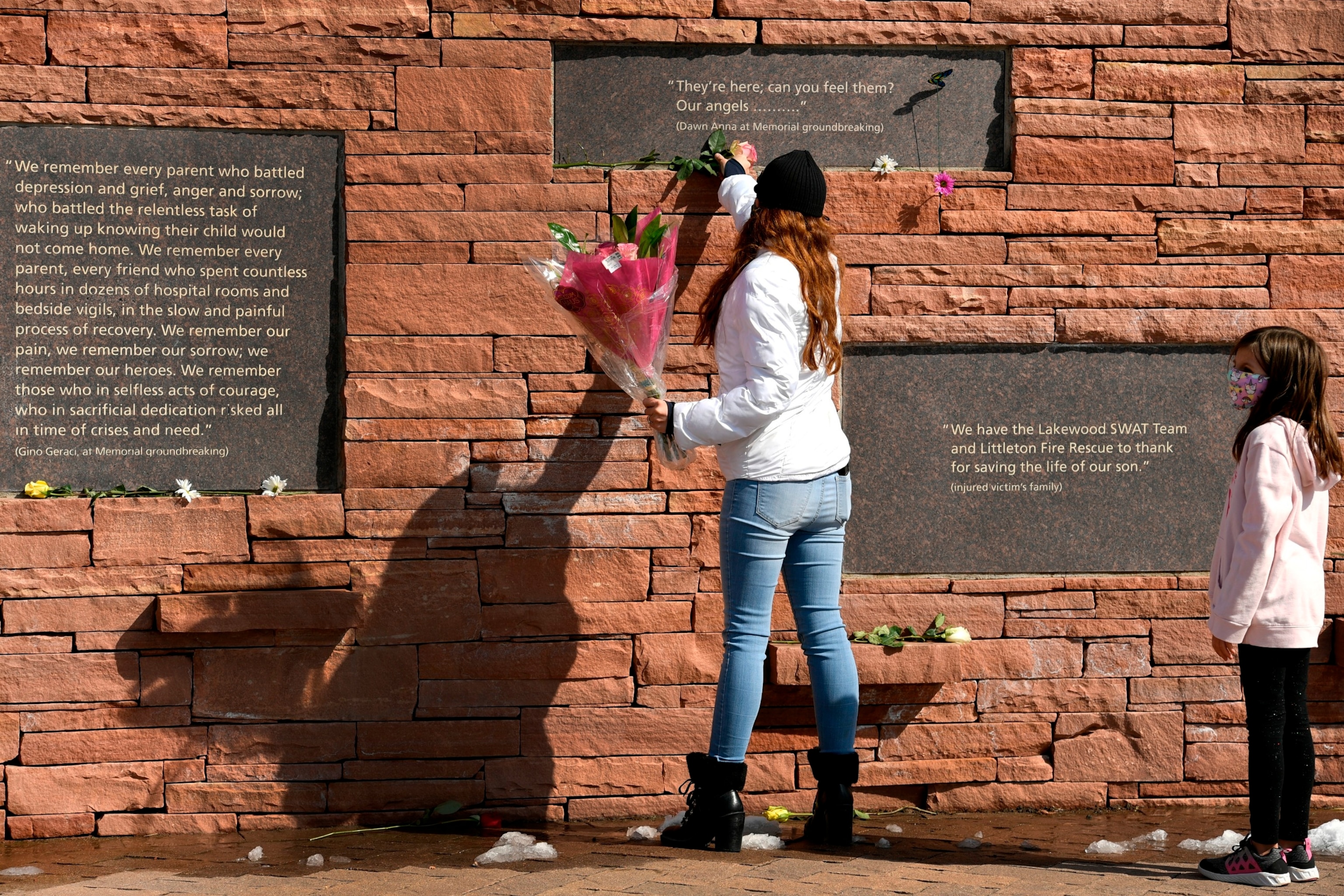 PHOTO: Brandy Munoz and her daughter Jazzy, leave flowers under placards with quotes at the Columbine Memorial at Robert F. Clement Park, Apr. 20, 2021, in Littleton, Colorado. 