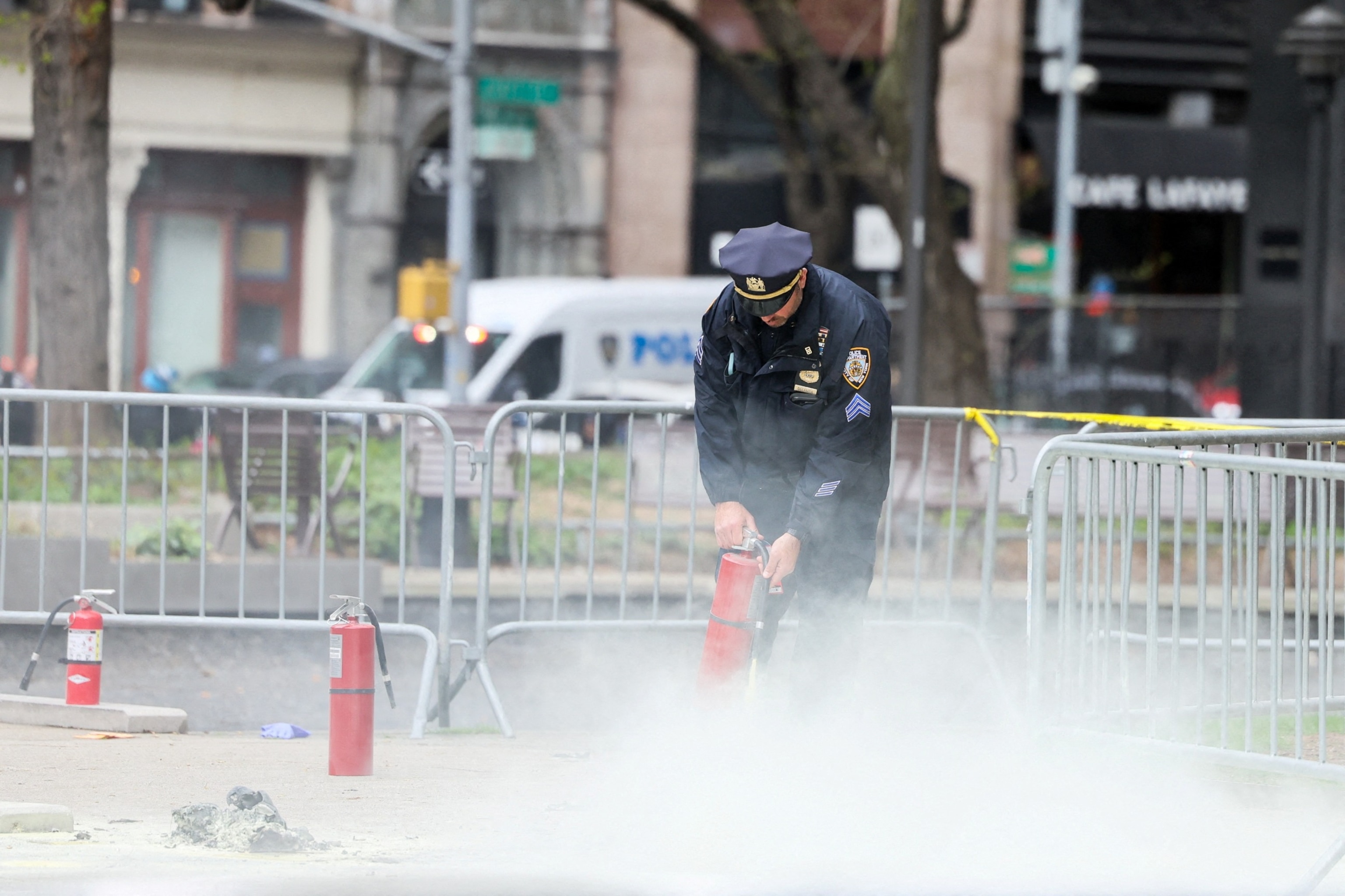 PHOTO: A police officer uses a fire extinguisher as emergency personnel respond to a report of a person covered in flames, outside the courthouse where former President Donald Trump's trial in New York, April 19, 2024. 