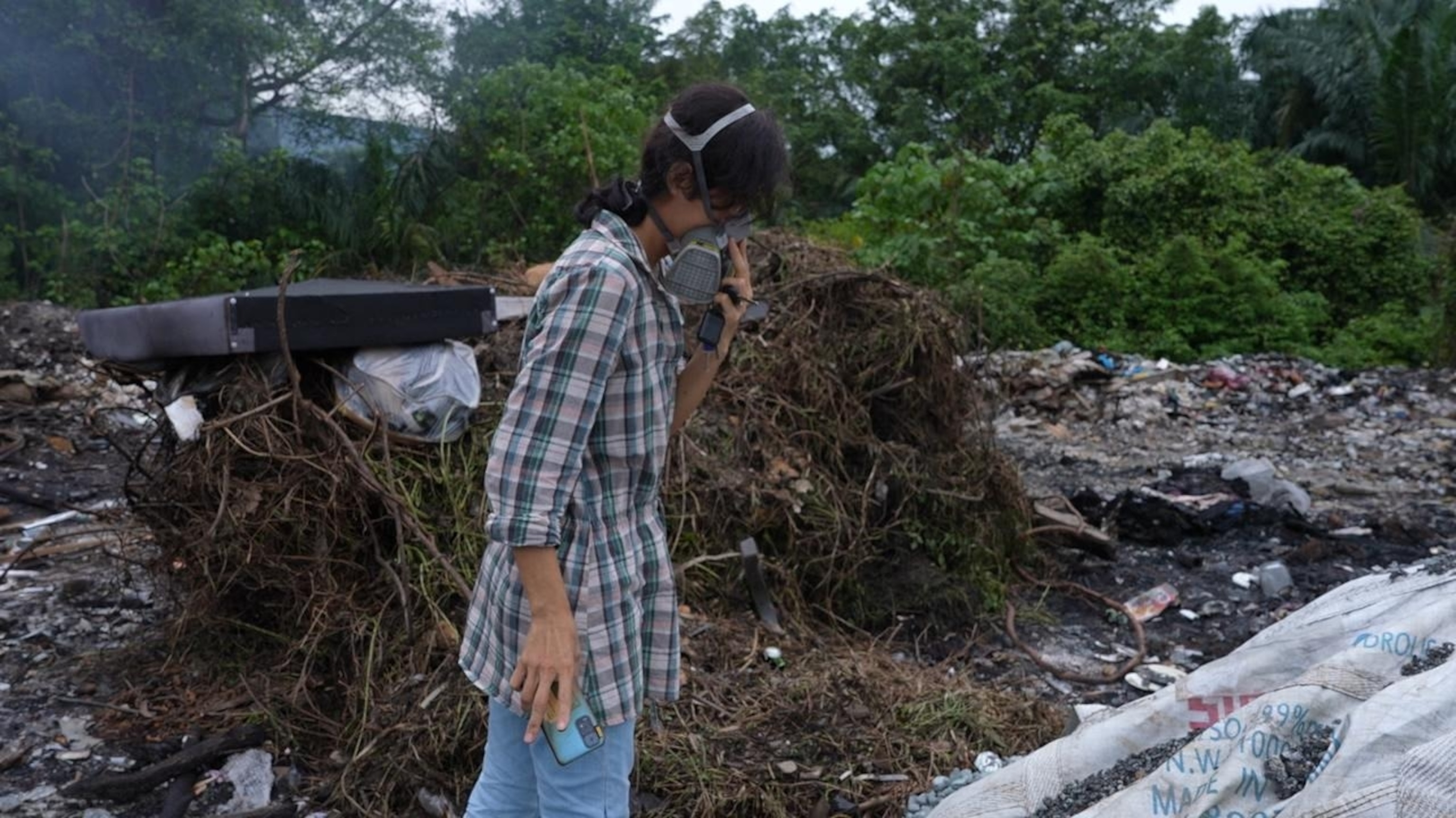 PHOTO: Malaysian anti-plastics advocate Pua Lay Peng searching through a burning dumpsite outside a plastic facility near her hometown of Jenjarom, Malaysia.