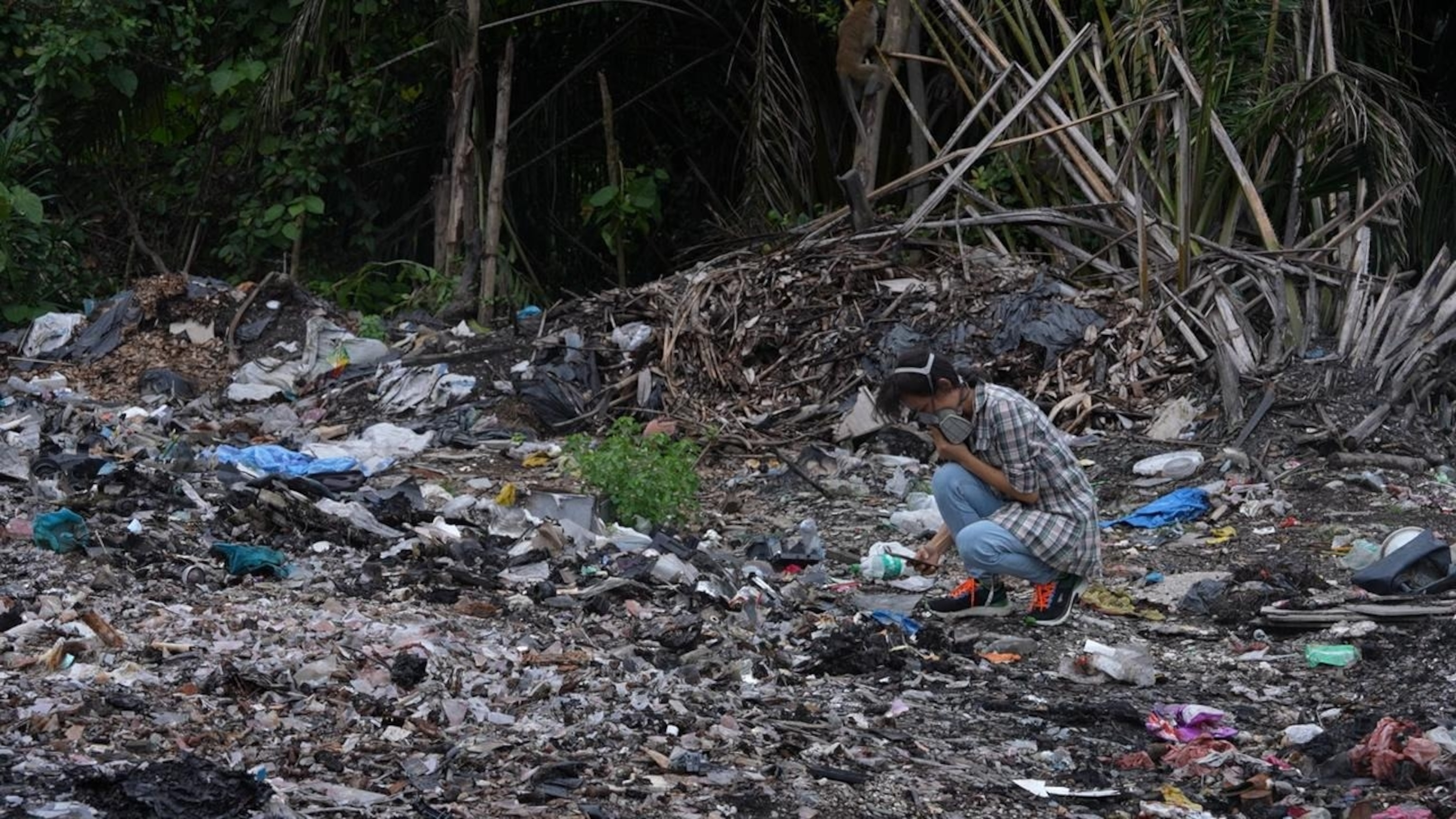 PHOTO: Malaysian anti-plastics advocate Pua Lay Peng searching through a burning dumpsite outside a plastic facility near her hometown of Jenjarom, Malaysia.