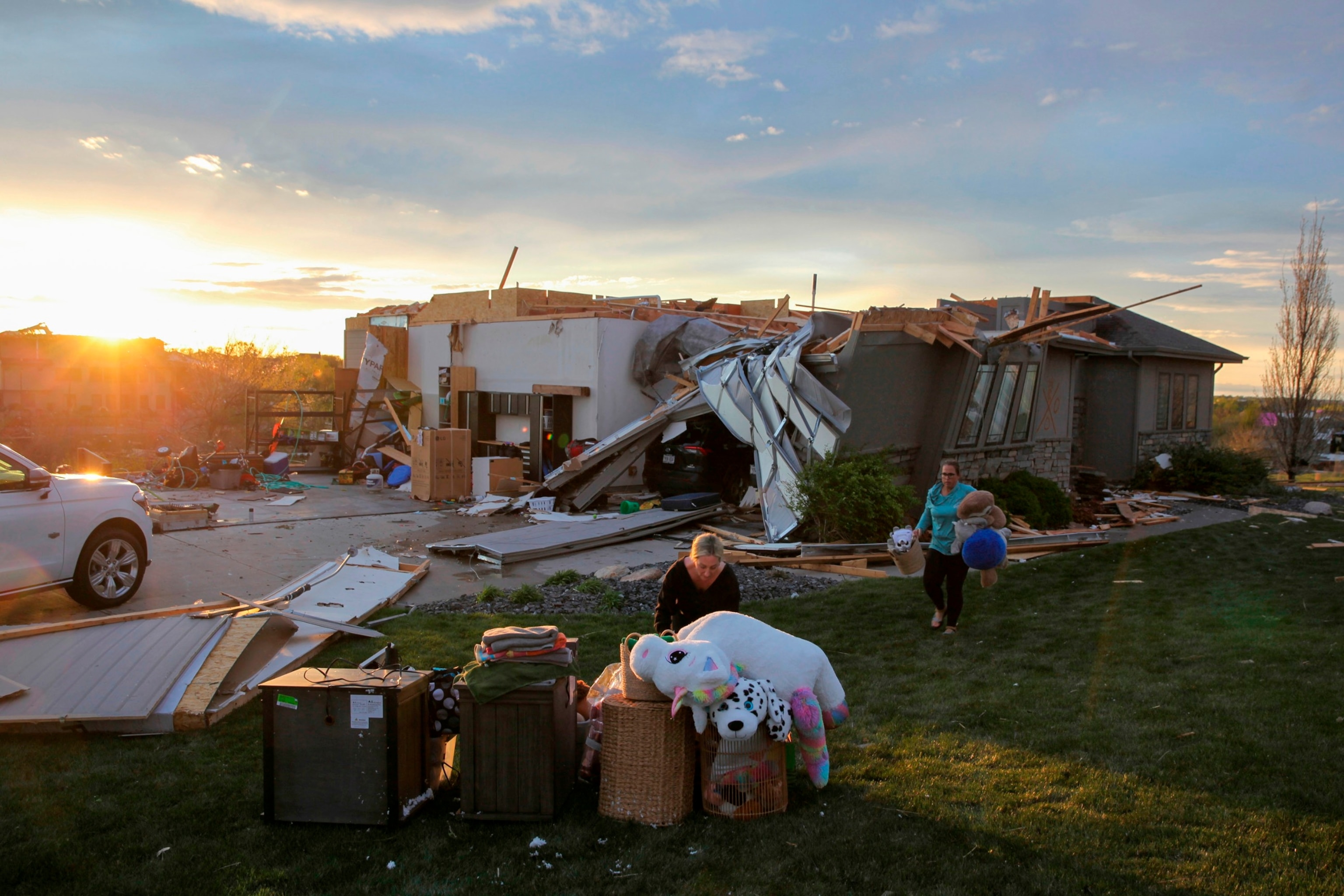PHOTO: Two women help carry a friend's belongings out of their damaged home after a tornado passed through the area in Bennington, Neb., on April 26, 2024.