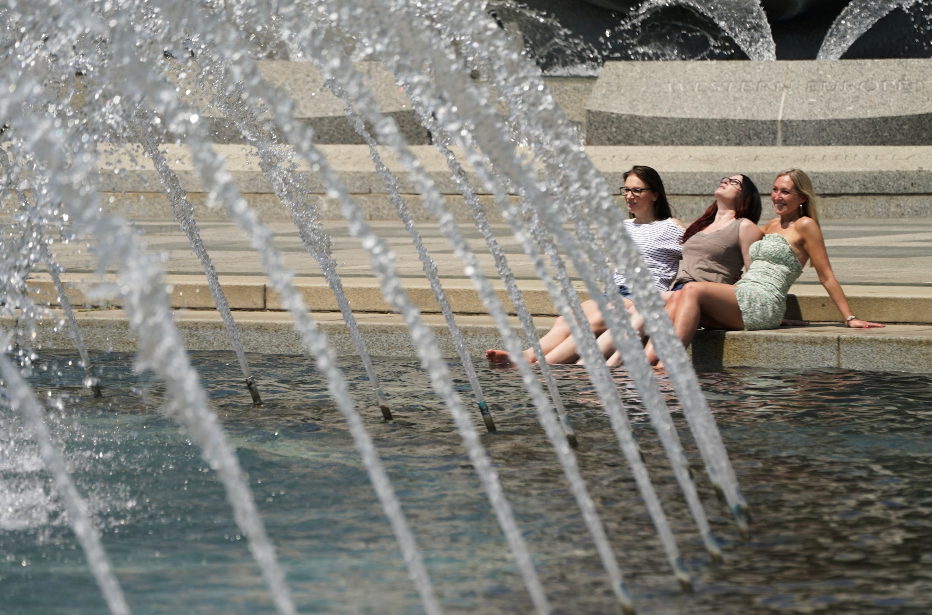PHOTO: Women dip their feet in the cool fountain at the World War II Memorial on a possible record setting heat day in Washington, D.C., April 29, 2024. 