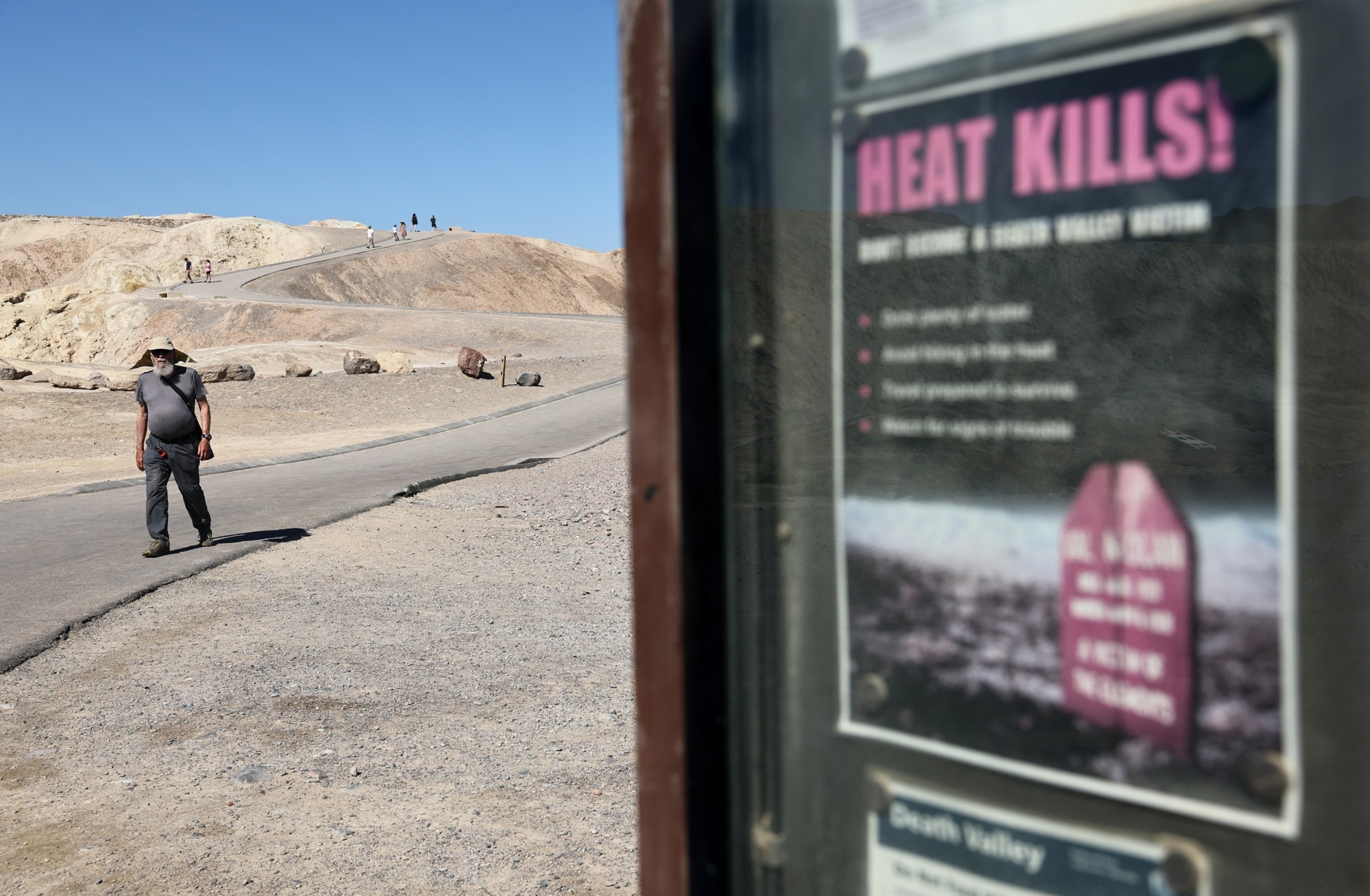 PHOTO: A 'Heat Kills' sign is posted as visitors walk nearby, April 23, 2024, in Death Valley National Park, Calif.