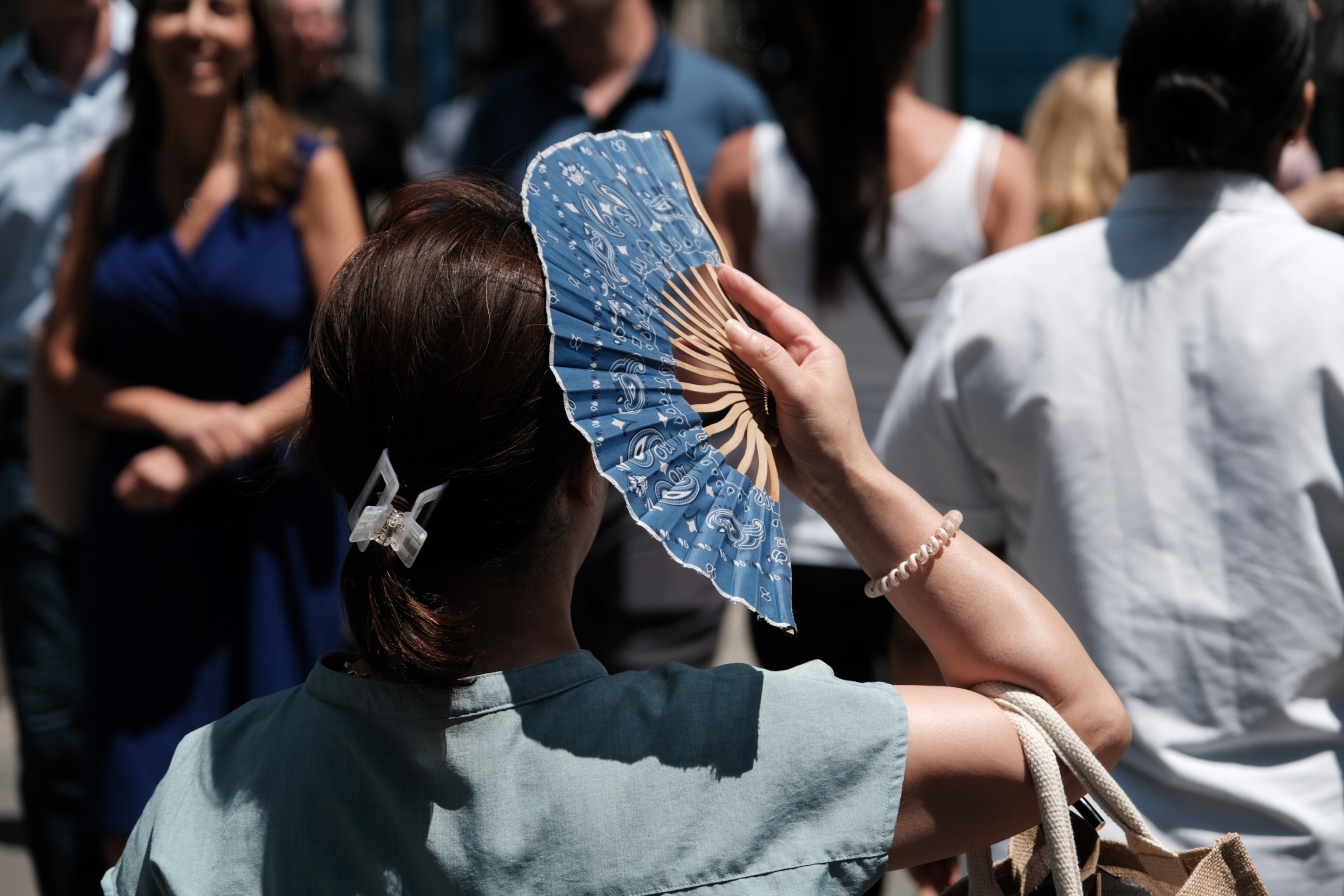PHOTO: A woman walks with a hand fan on a hot afternoon in midtown Manhattan on July 06, 2023 in New York City. 