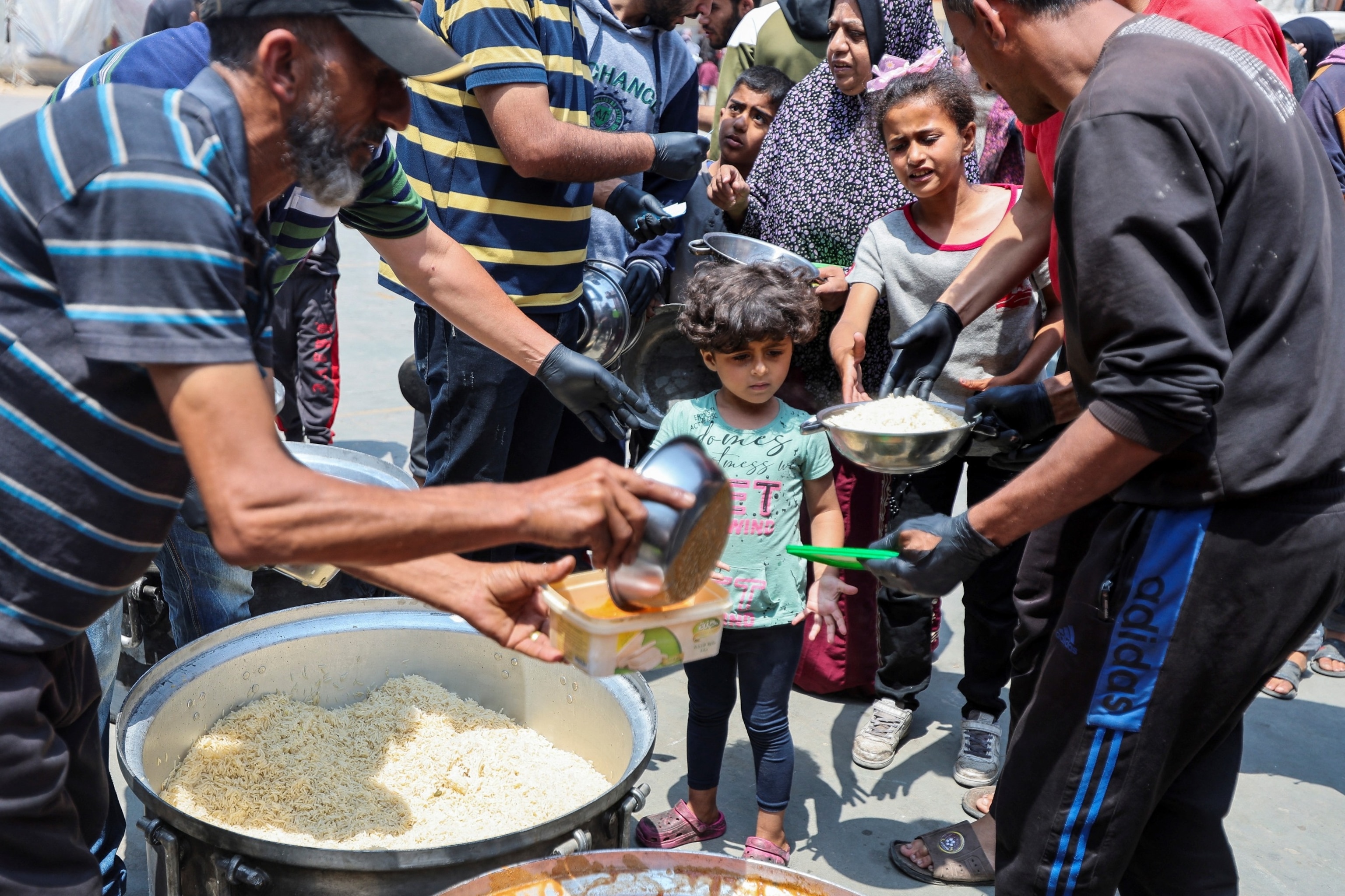 PHOTO: Palestinians gather to receive food meals cooked by World Central Kitchen after the charity resumed operations at a school sheltering displaced people in Deir Al-Balah in the central Gaza Strip, May 1, 2024. 