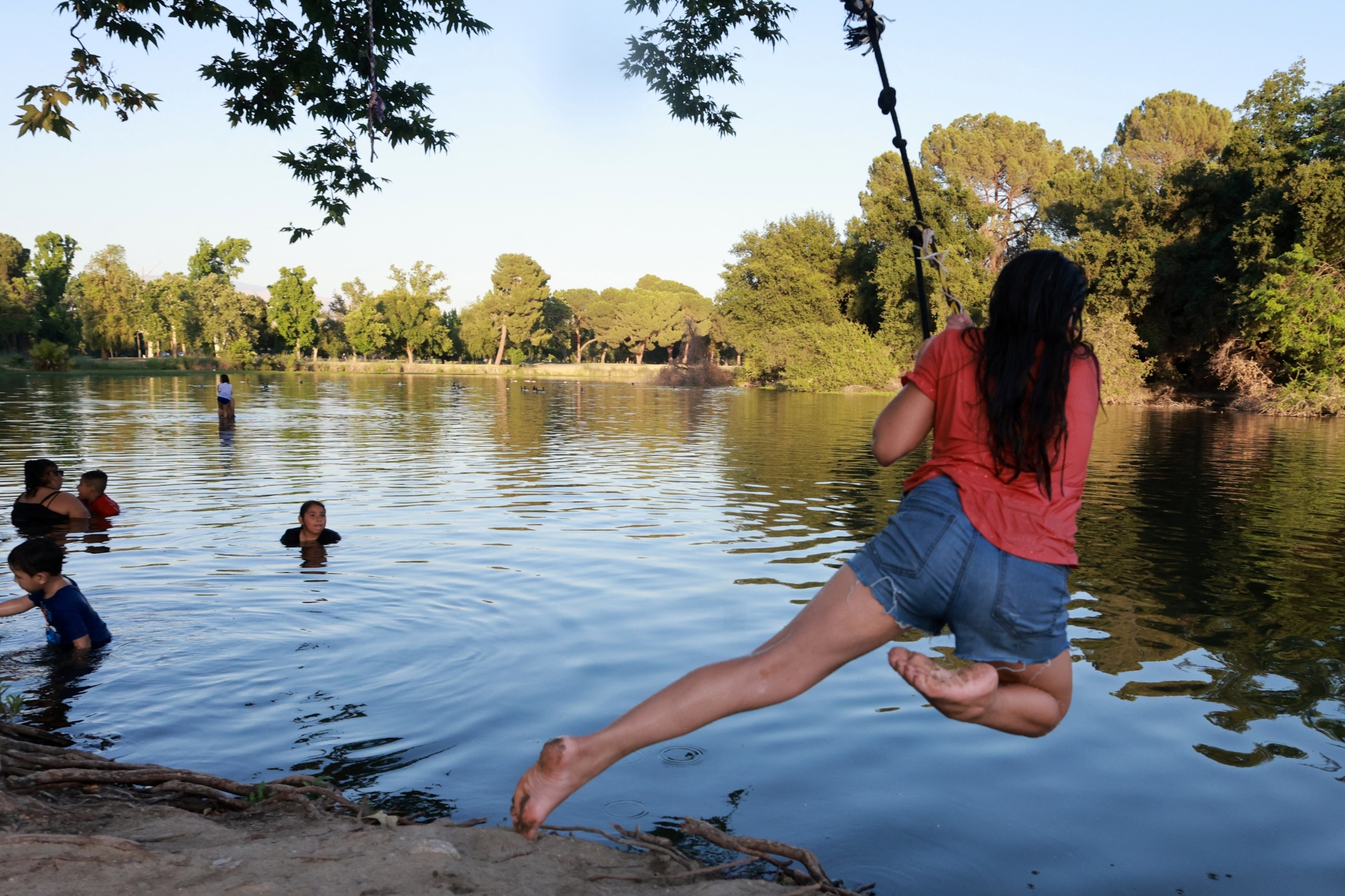 PHOTO: A child jumps into the water using a rope swing to find relief from the over 100 degrees Fahrenheit temperature at the lake in Hart Memorial Park in Bakersfield, California, on June 5, 2024.