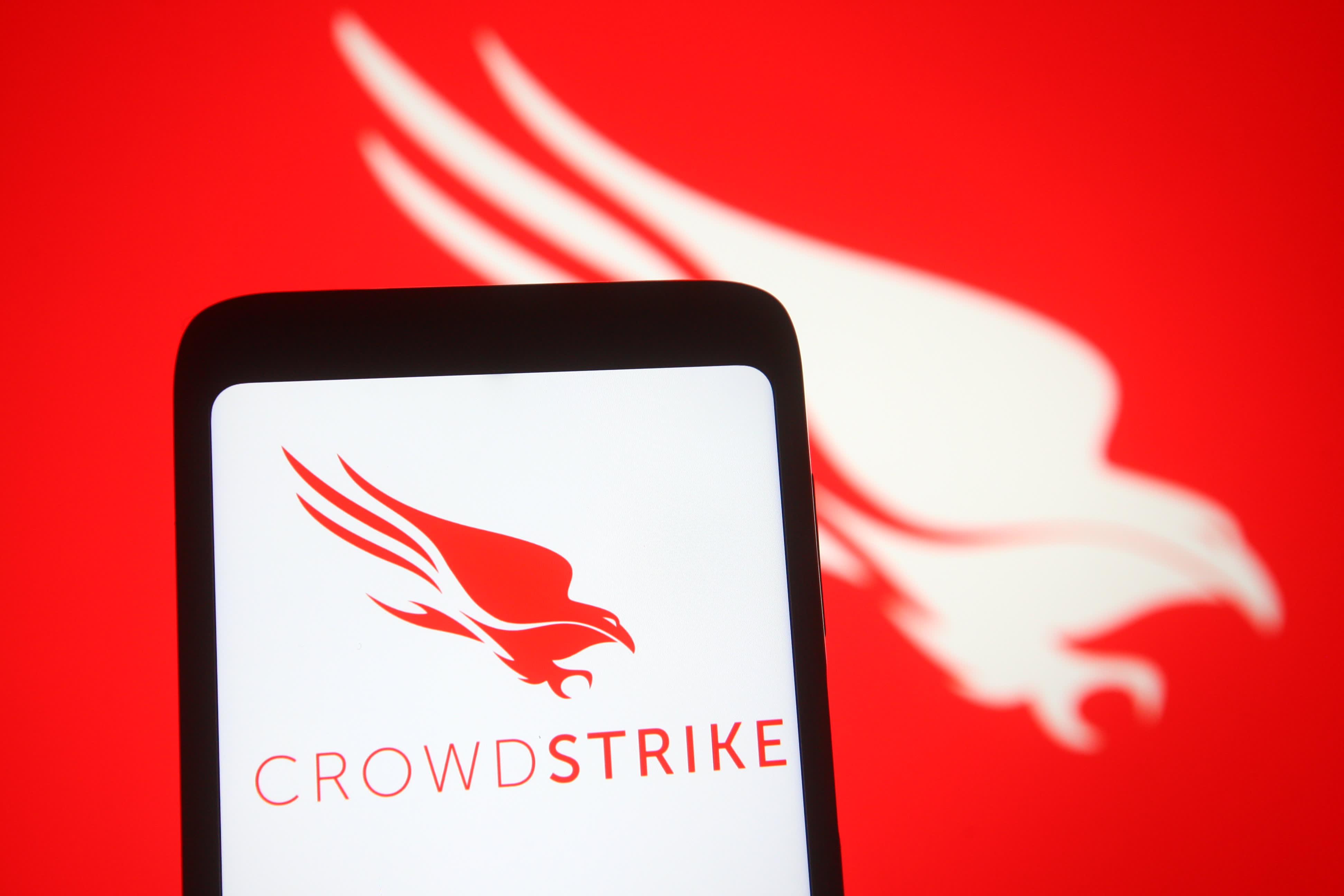 In this photo illustration, CrowdStrike logo of a U.S. cybersecurity technology company is seen on a smartphone and a pc screen.