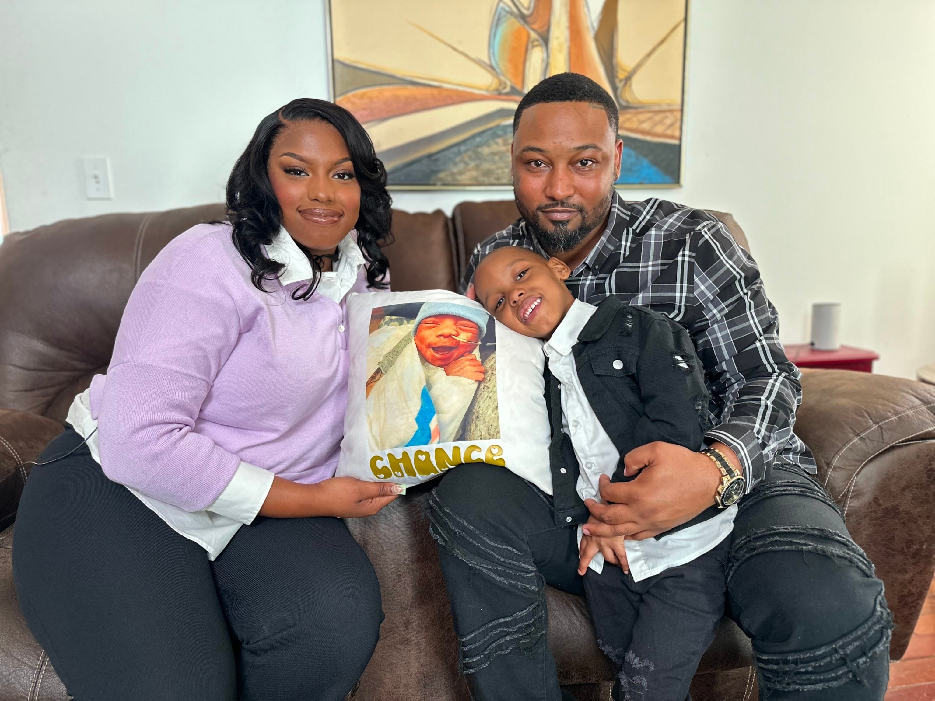 PHOTO: Jasmine Watson sits with her partner, Cedric Dean, and their son Chase, 4. Pictured on the pillow is Chance Dean, who died from NEC in March, 2020.