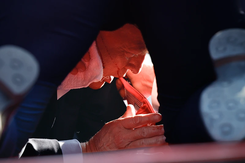 Donald Trump Holds A Campaign Rally In Butler, Pennsylvania
BUTLER, PENNSYLVANIA - JULY 13: Secret Service tend to republican presidential candidate former President Donald Trump onstage after he was grazed by a bullet at a rally on July 13, 2024 in Butler, Pennsylvania. Butler county district attorney Richard Goldinger said the shooter is dead after injuring former President Trump, killing one audience member and injuring another in the shooting. (Photo by Anna Moneymaker/Getty Images)