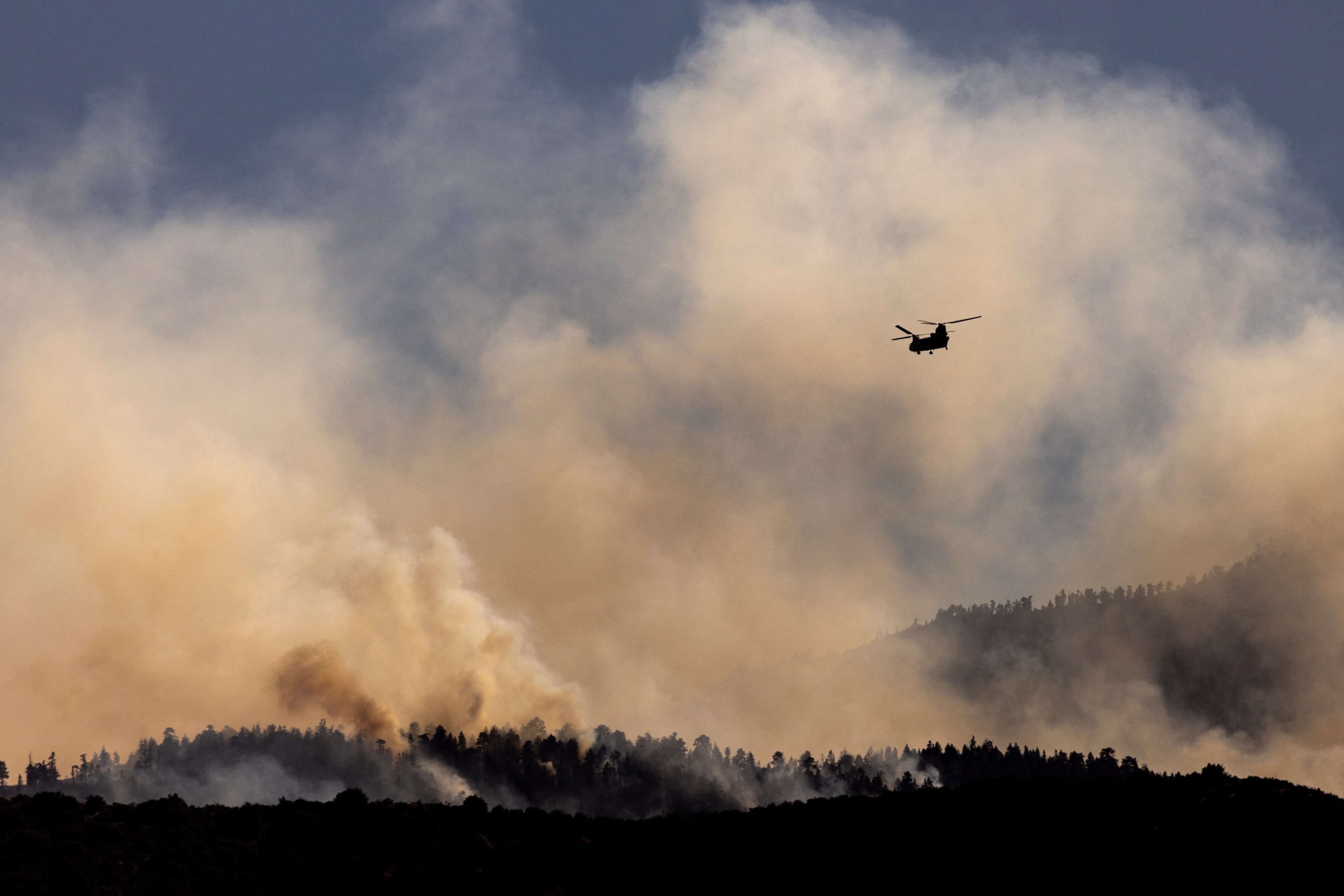 A firefighting Chinook helicopter flies over the smoke from the Bridge Fire burning in the hills overlooking Pinon Hills, California, on September 12, 2024. (Photo by ETIENNE LAURENT / AFP) (Photo by ETIENNE LAURENT/AFP via Getty Images)