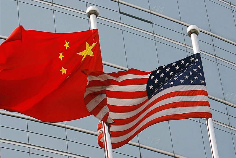 Beijing, CHINA: A US and a Chinese flag wave outside a commercial building in Beijing, 09 July 2007. US Secretary of State Condoleezza Rice 06 July 2007 accused China of flouting the rules of global trade in its headlong economic expansion as the US administration "has not been hesitant" to deploy trade tools against China, including a complaint lodged with the World Trade Organization over copyright piracy. AFP PHOTO/TEH ENG KOON (Photo credit should read TEH ENG KOON/AFP via Getty Images)