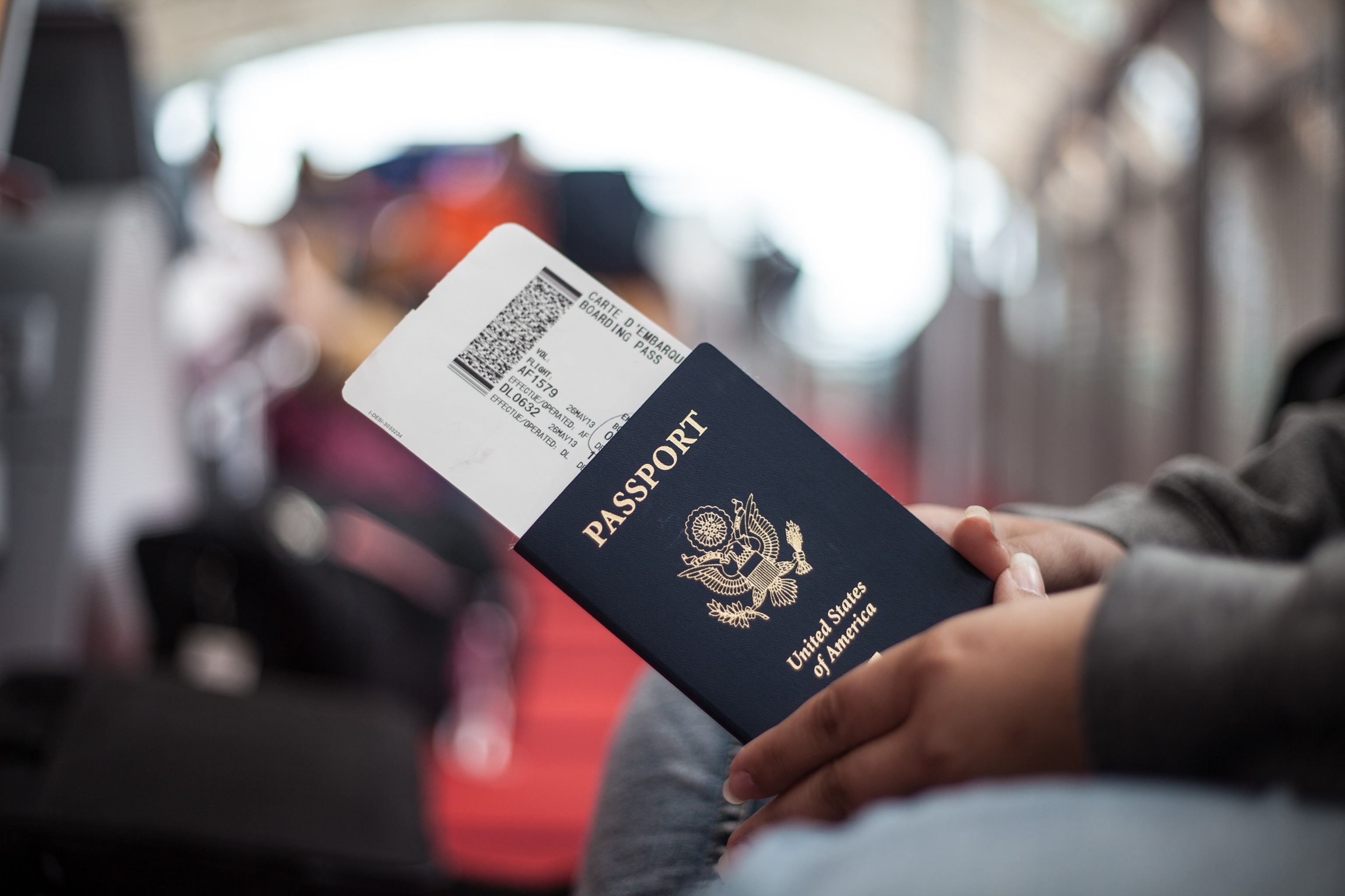 PHOTO: Close Up of a person holding an American Passport at an airport.