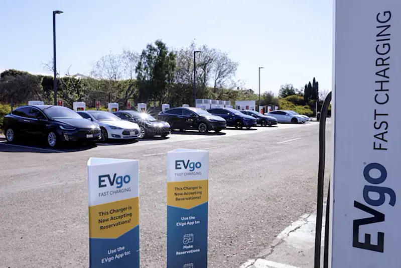 People charge their electric cars at a Tesla super charging station next to an EVgo electric charging location in Carlsbad, California, U.S., March 7, 2022. REUTERS/Mike Blake/File Photo