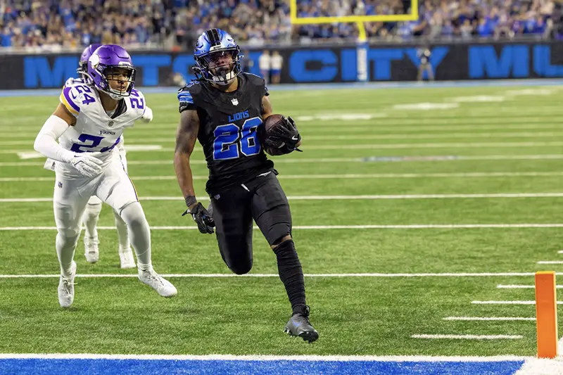 Detroit Lions running back Jahmyr Gibbs (26) runs with the ball in front of Minnesota Vikings safety Camryn Bynum (24) and scores a touchdown during the second half at Ford Field. Mandatory Credit: David Reginek-Imagn Images