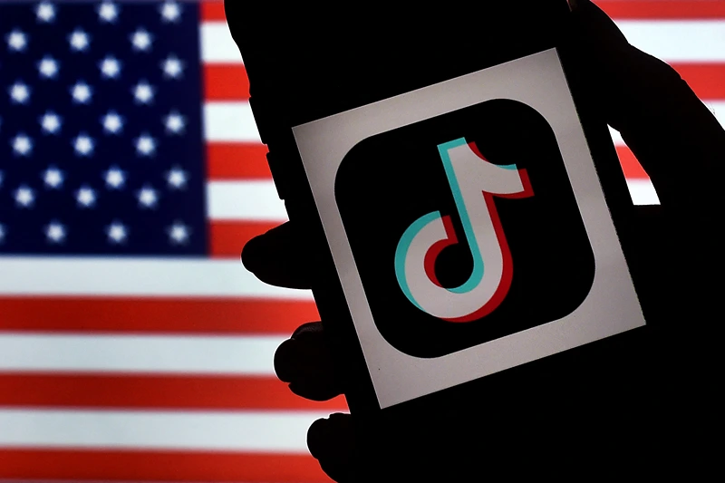 US-IT-CHINA-POLITICS-TIKTOK In this photo illustration, the social media application logo, TikTok is displayed on the screen of an iPhone on an American flag background on August 3, 2020 in Arlington, Virginia. - The US Senate voted on August 6, 2020, to bar TikTok from being downloaded onto US government employees' telephones, intensifying US scrutiny of the popular Chinese-owned video app. The bill passed by the Republican controlled Senate now goes to the House of Representatives, led by Democrats. (Photo by Olivier DOULIERY / AFP) (Photo by OLIVIER DOULIERY/AFP via Getty Images)