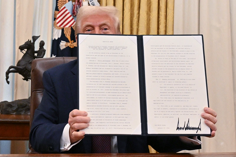 US President Donald Trump holds the executive order he signed to declassify the files of slained former President John F. Kennedy, former Attorney General Robert F. Kennedy and civil rights leader Martin Luther King Jr., in the Oval Office of the White House in Washington, DC, on January 23, 2025. (Photo by ROBERTO SCHMIDT / AFP) (Photo by ROBERTO SCHMIDT/AFP via Getty Images)