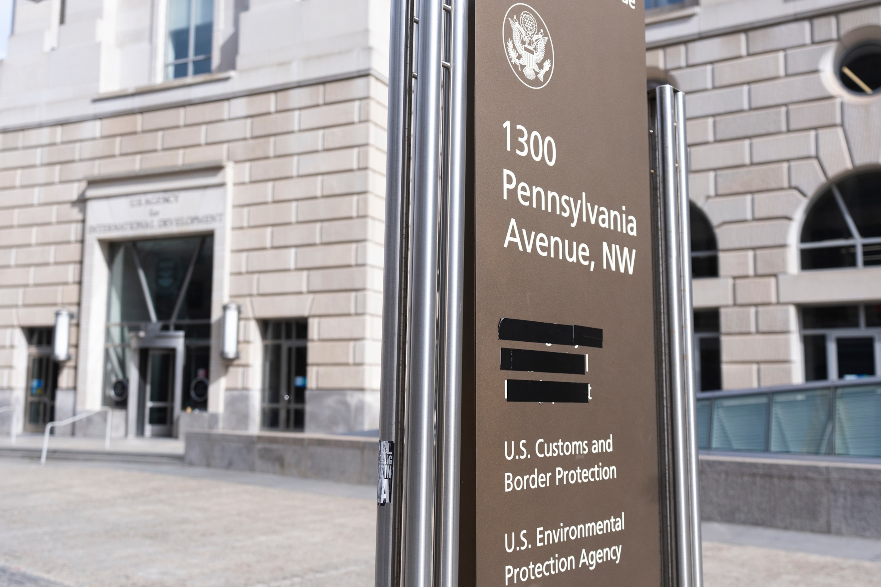 PHOTO: A street sign with names of U.S. government agencies housed at the Ronald Reagan Building is pictured with one building occupant taped, on Feb. 7, 2025, in Washington, D.C.