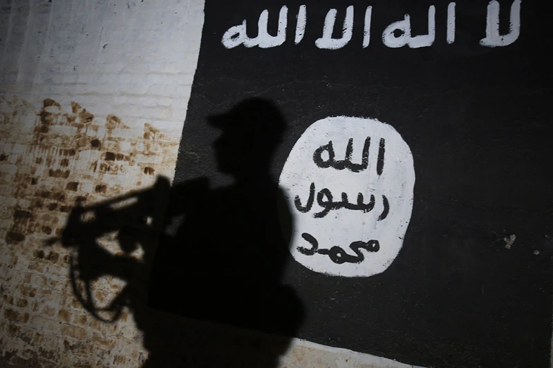 A member of the Iraqi forces walks past a mural bearing the logo of the Islamic State (IS) group in a tunnel that was reportedly used as a training centre by the jihadists, on March 1, 2017, in the village of Albu Sayf, on the southern outskirts of Mosul. Iraqi forces launched a major push on February 19 to recapture the west of Mosul from the Islamic State jihadist group, retaking the airport and then advancing north. (Photo by AHMAD AL-RUBAYE / AFP) (Photo by AHMAD AL-RUBAYE/AFP via Getty Images)