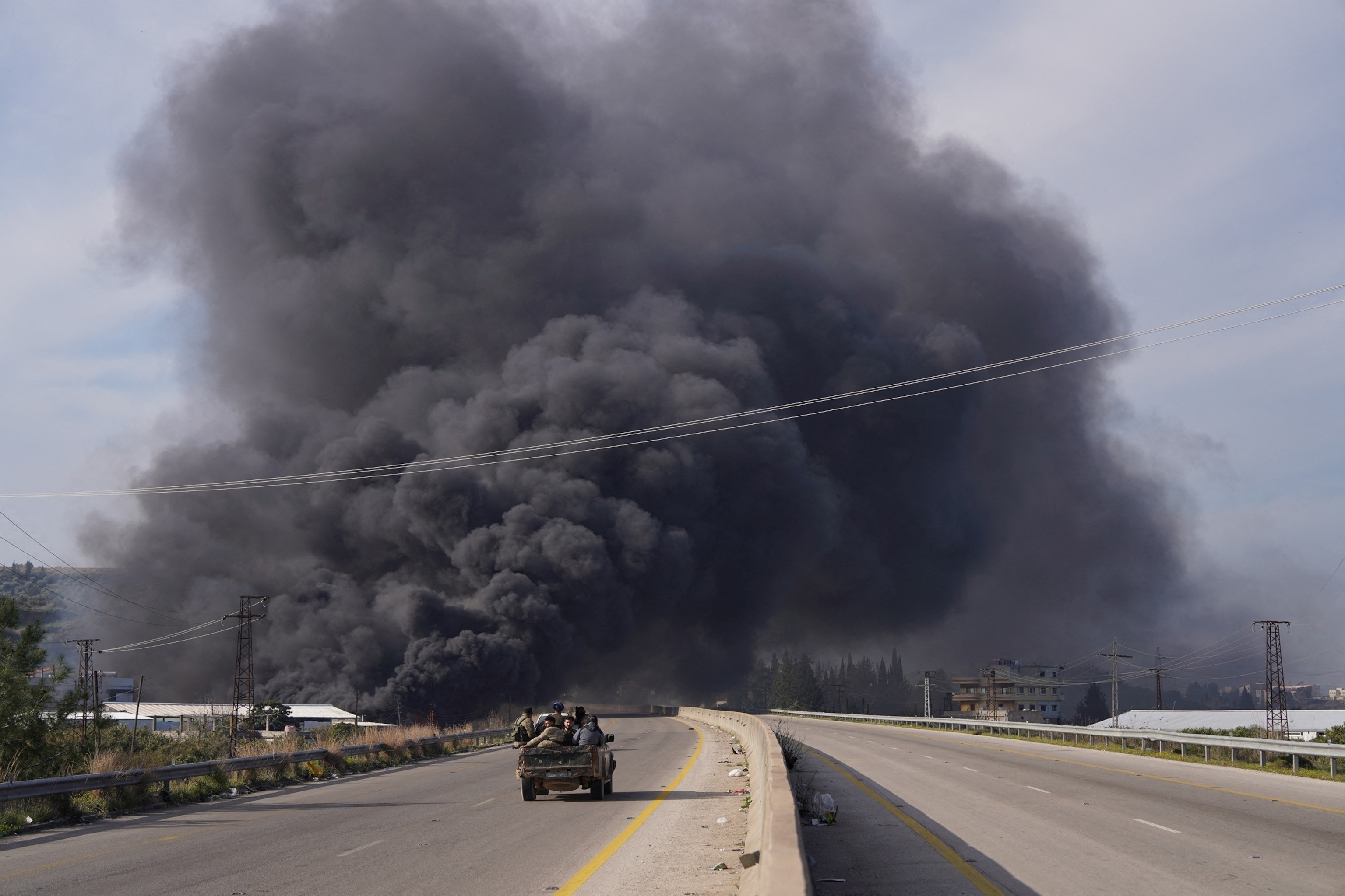 PHOTO: Smoke rises while members of the Syrian forces ride on a vehicle in Latakia